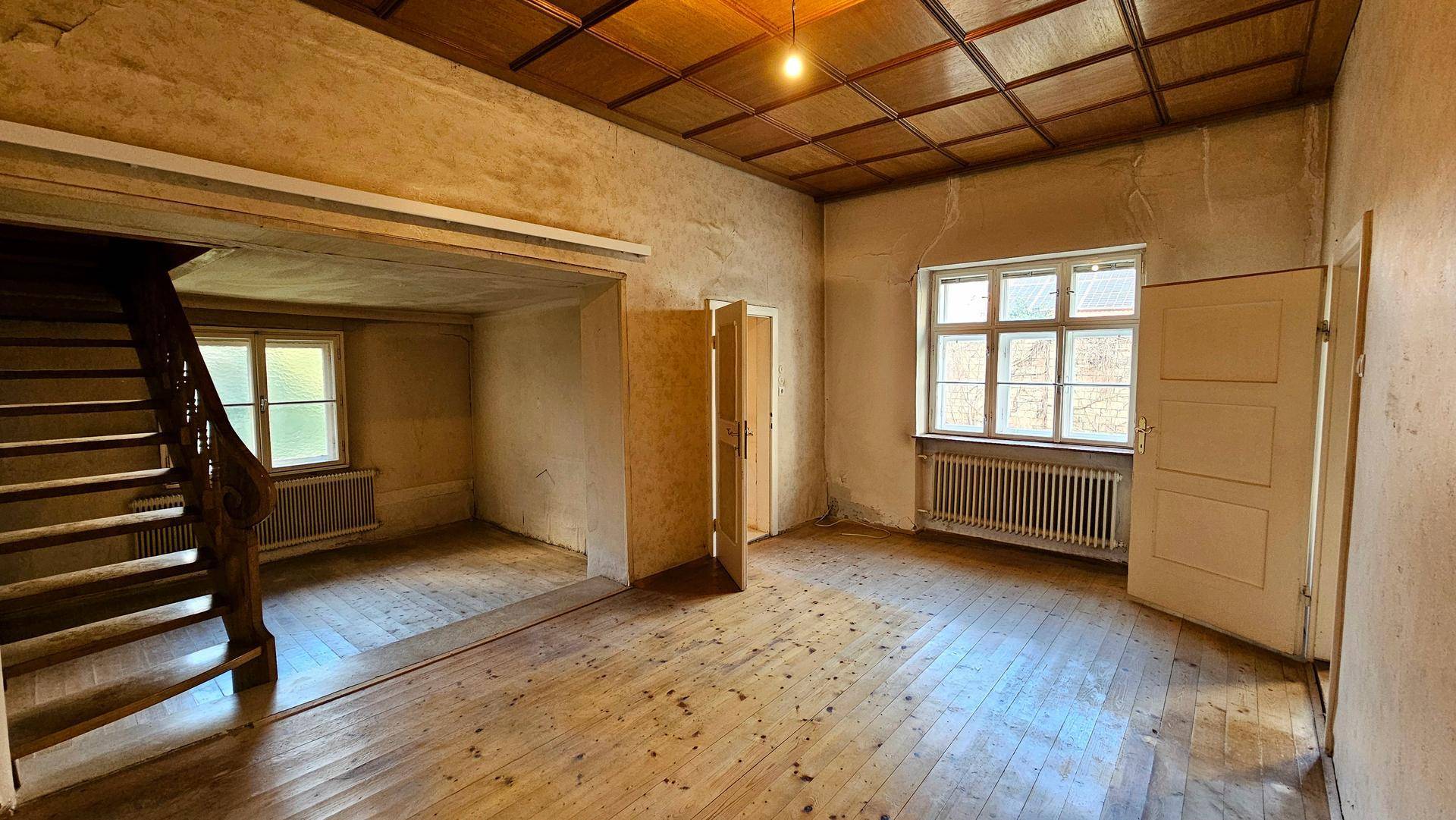 Wohnraum mit Holztreppe, Holzdielenboden und einer Holzdeckenverkleidung.