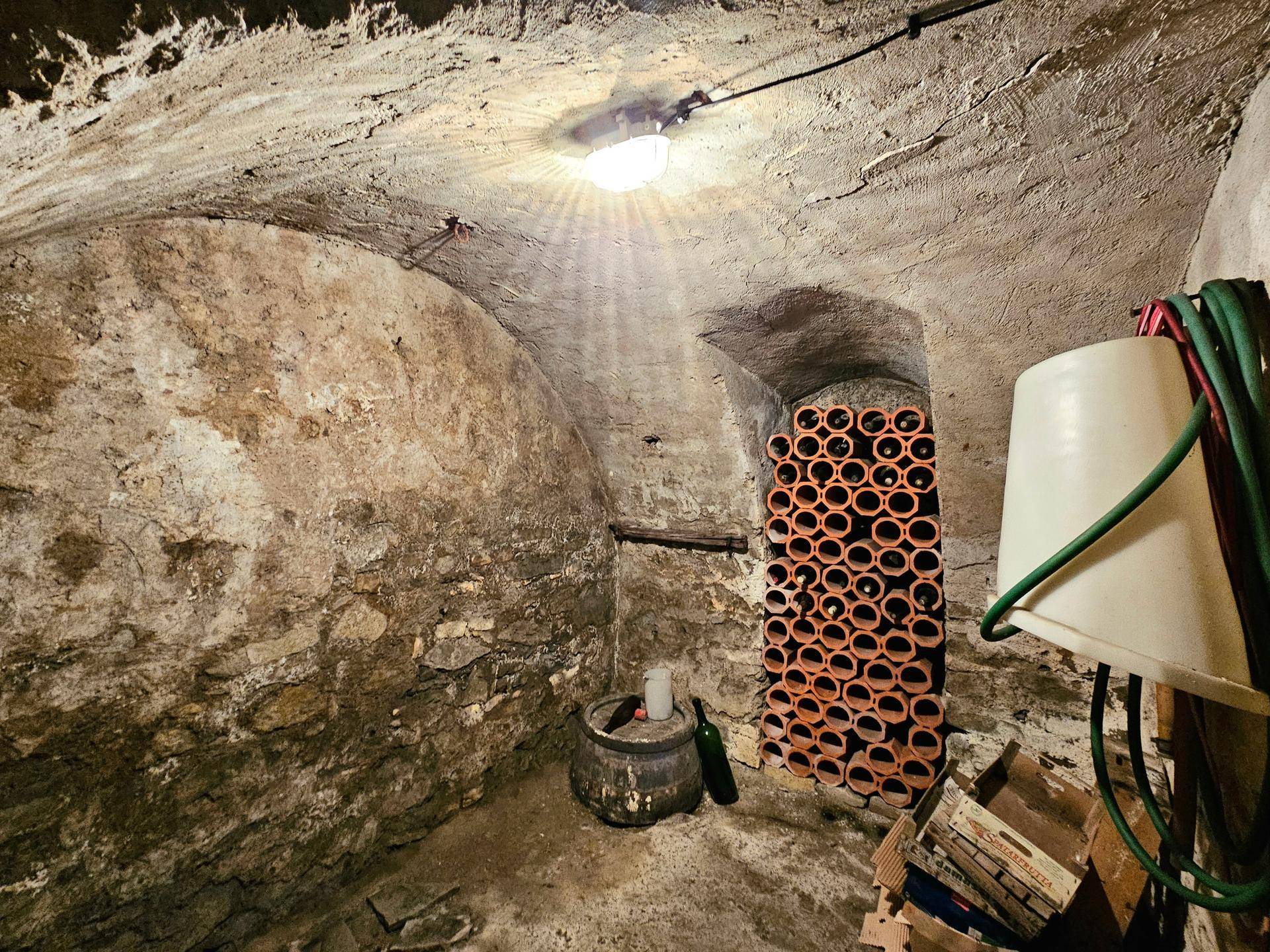 Gewölbekeller mit Steinwänden und Weinregalen, ideal zur Lagerung von Wein.