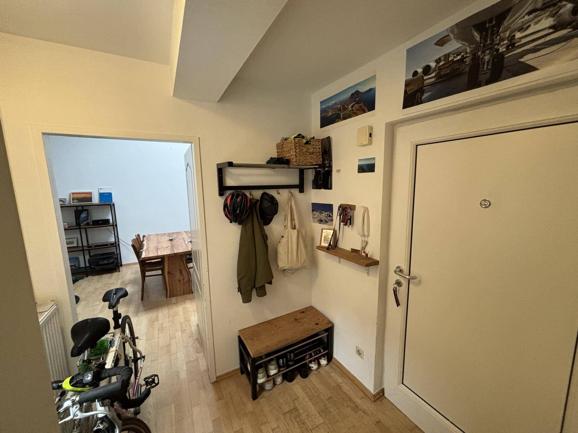 Heller Eingangsbereich mit Garderobe, Schuhregal und Zugang zum offenen Wohnbereich.
