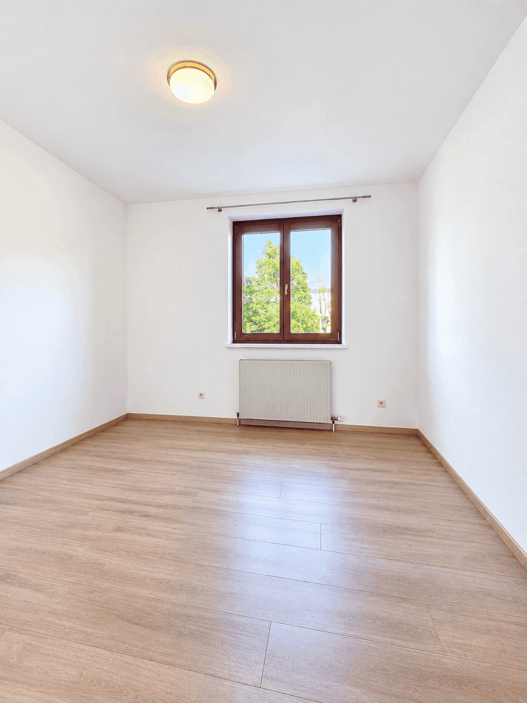 Freundliches Zimmer mit Laminatboden und einem großen Fenster für gute Belichtung.