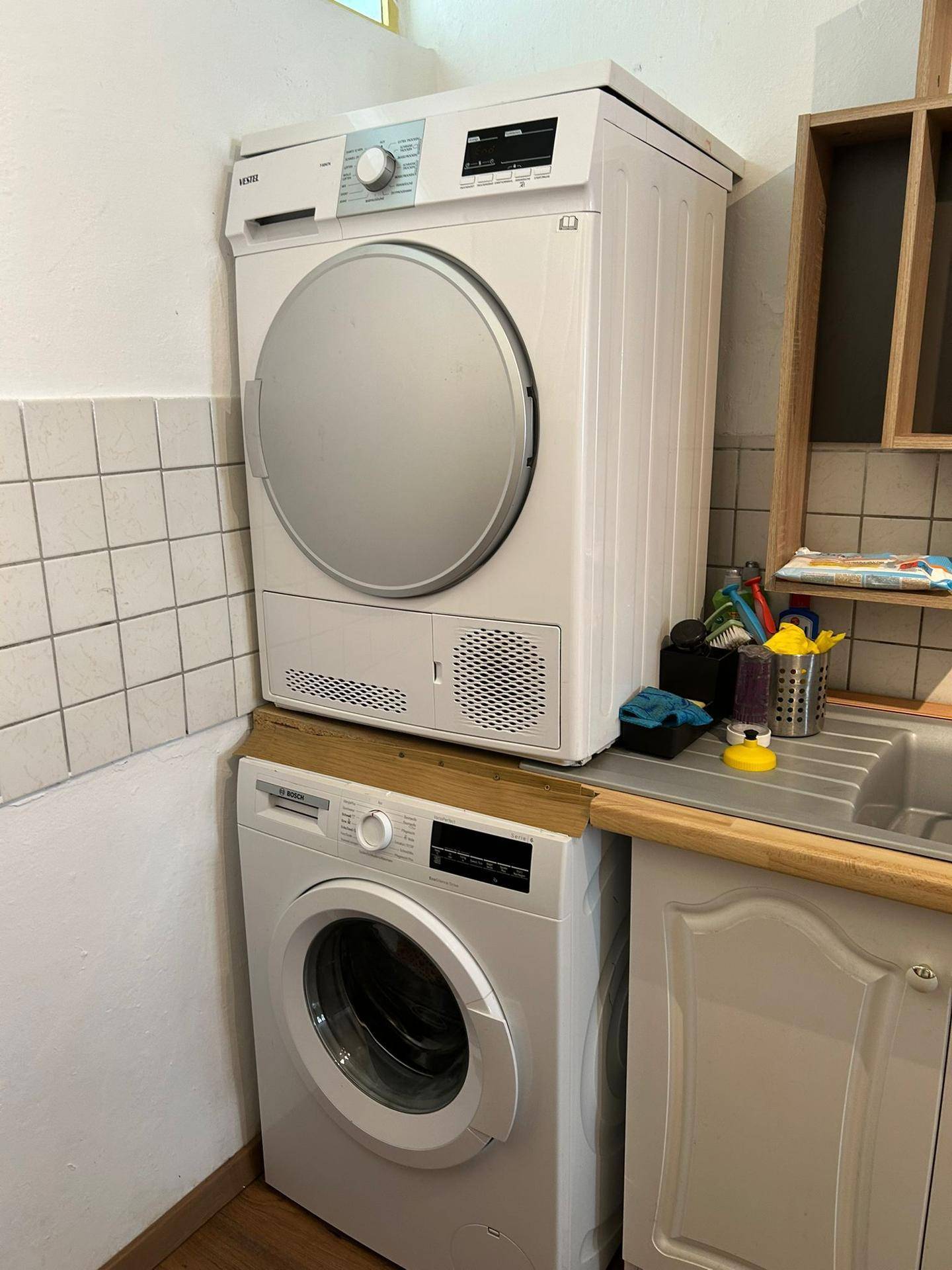 Nahaufnahme von Waschmaschine und Trockner, übereinander gestapelt in der Küche.