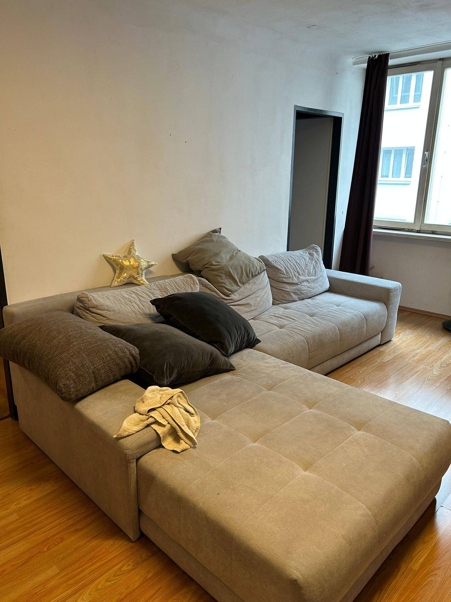 Gemütliches Wohnzimmer mit großem L-förmigem Sofa und Holzfußboden.