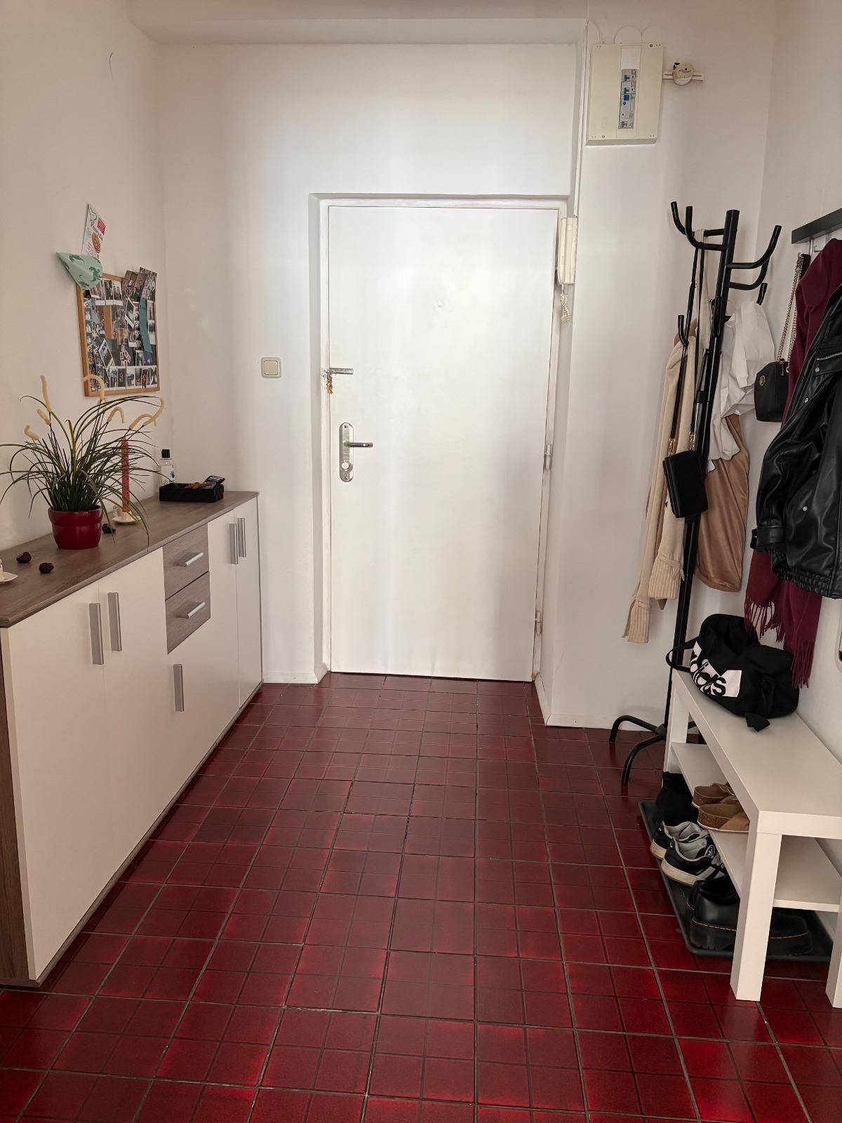 Eingangsbereich mit roten Fliesen, Garderobe und praktischem Schuhschrank.