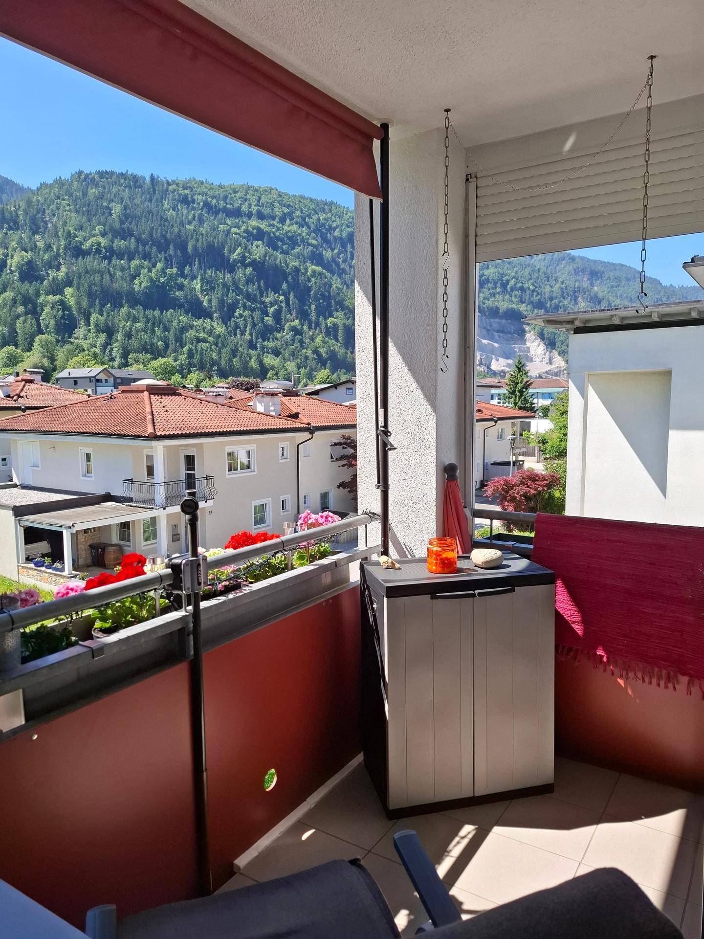 Heller Balkon mit Bergblick, Stauraum und Blumenkästen.