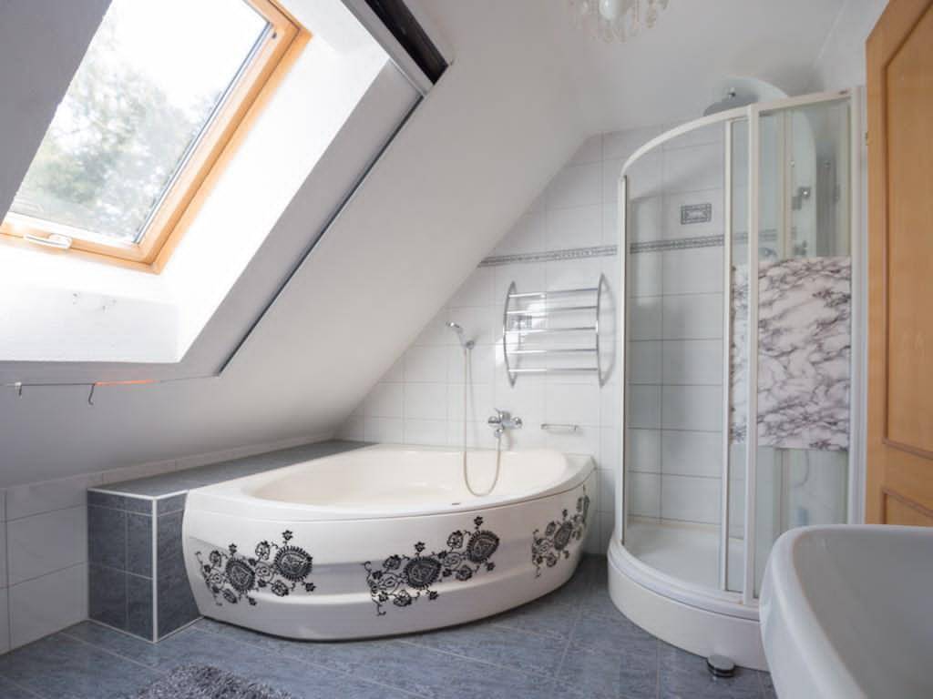 Badezimmer im Dachgeschoss mit Badewanne, Duschkabine und Dachfenster.