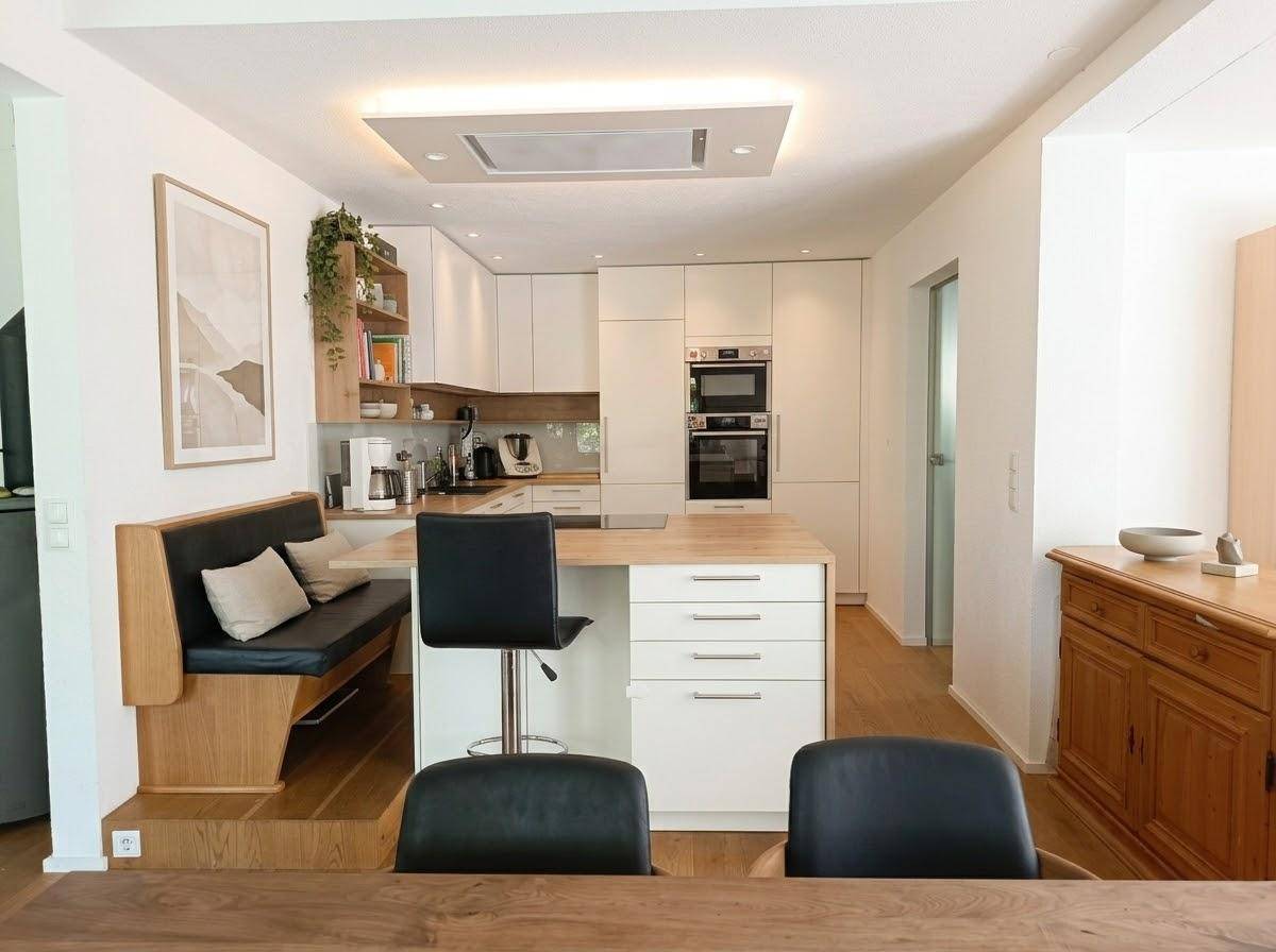 Moderne Einbauküche mit Kochinsel, integrierten Geräten und gemütlicher Essecke.