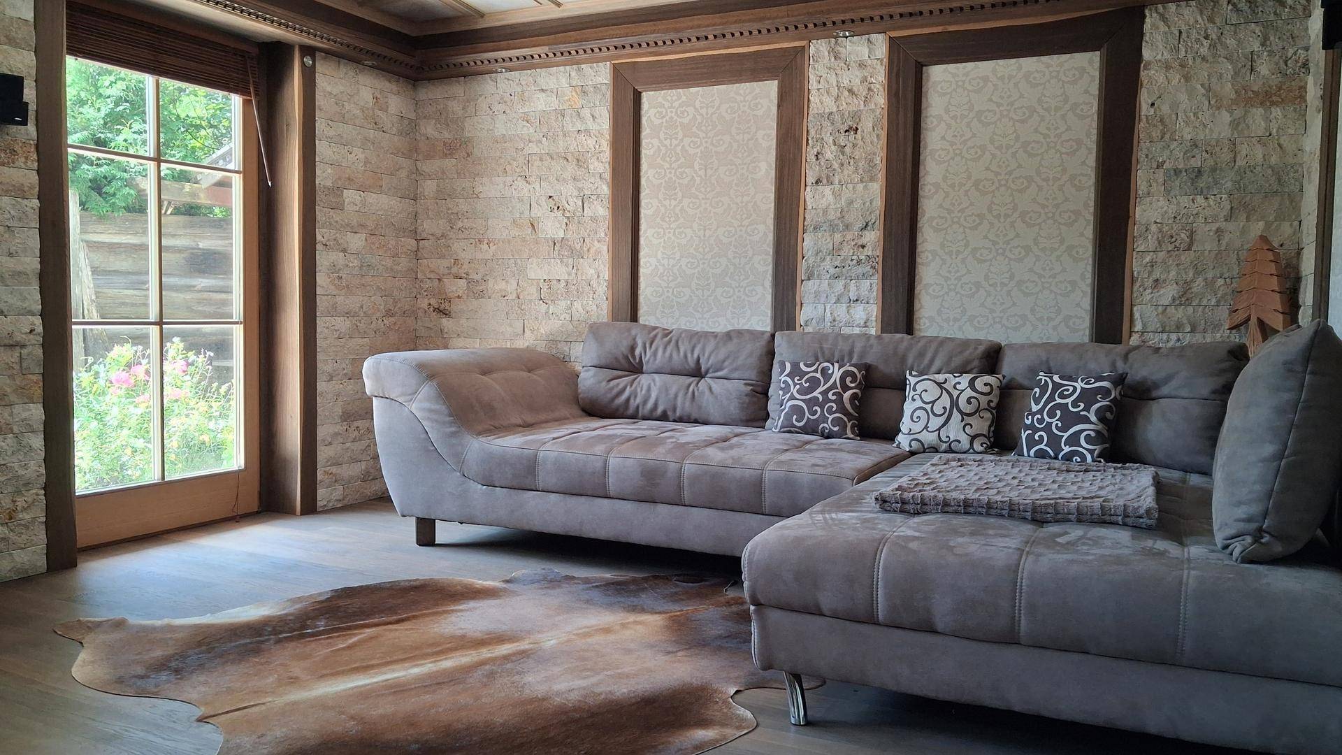 Heller Wohnbereich mit großem Ecksofa, Holzboden und Zugang zum Garten.