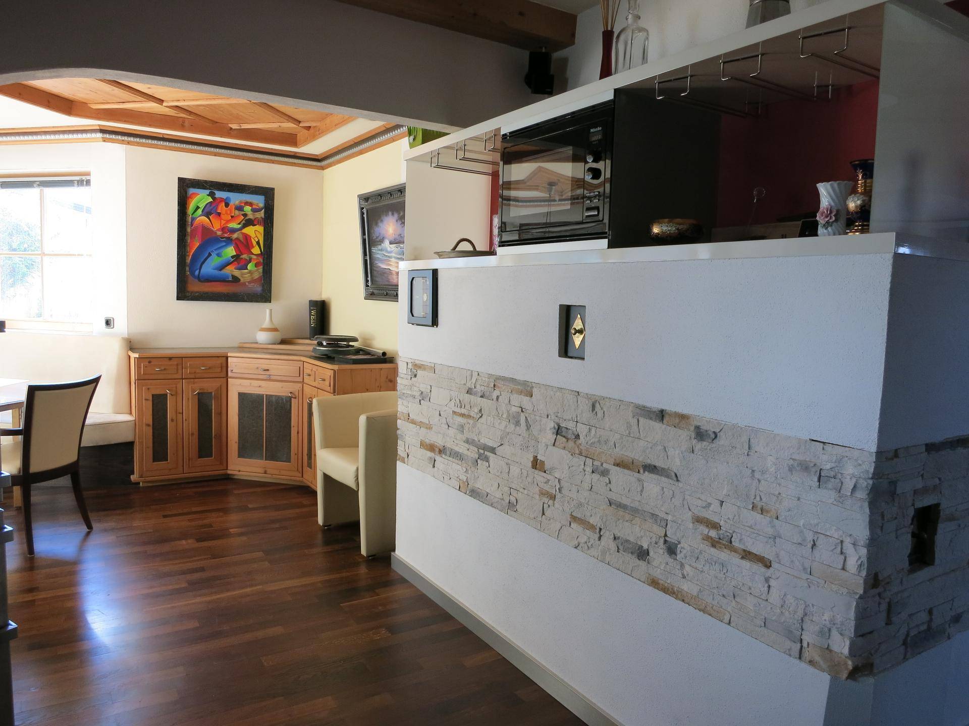 Essbereich mit Holzboden, Sideboard und einer Bar mit Steinverkleidung.