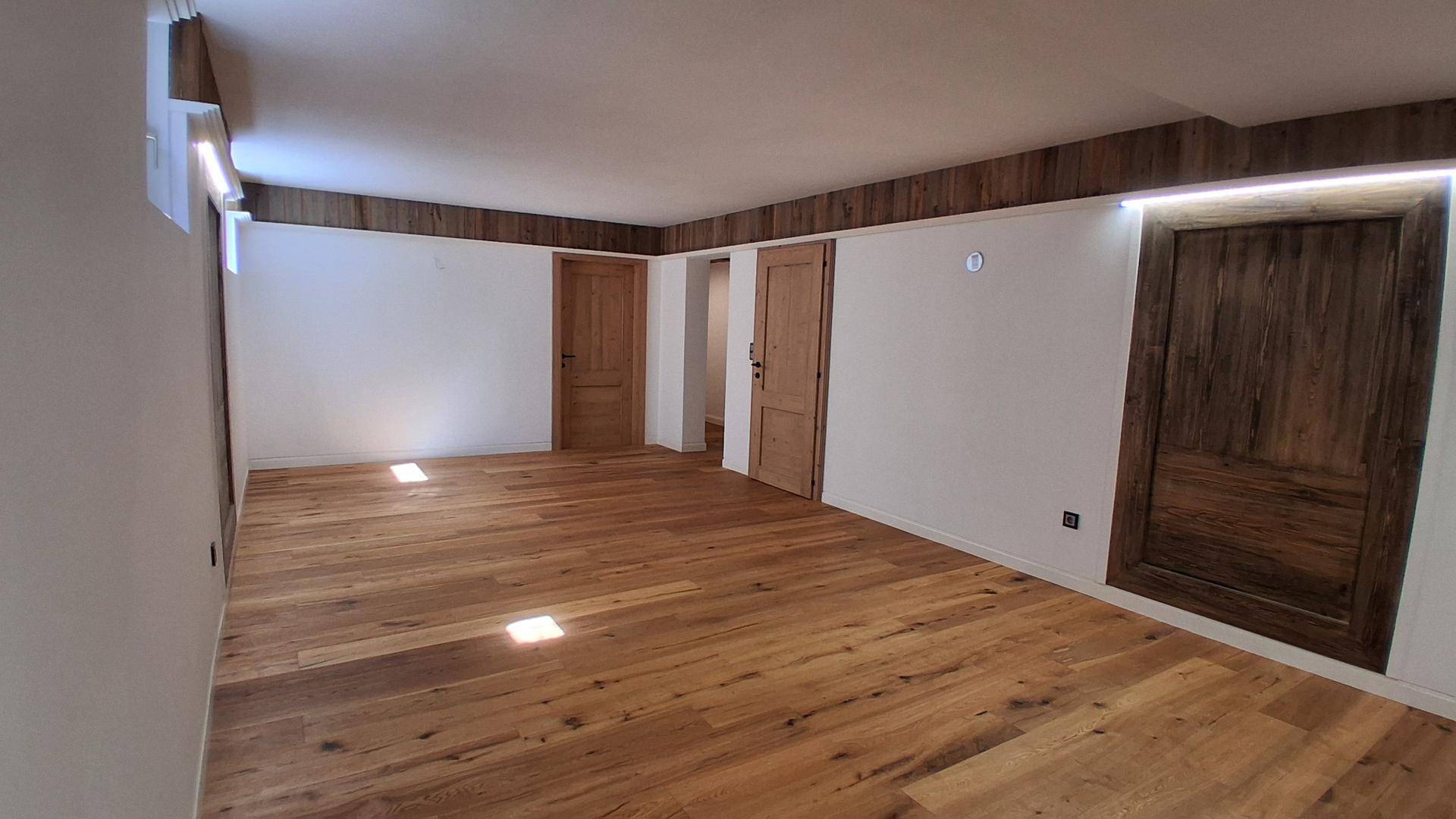 Geräumiges Zimmer mit warmem Holzplankenboden und schlichten weißen Wänden, bereit zur individuellen Gestaltung.