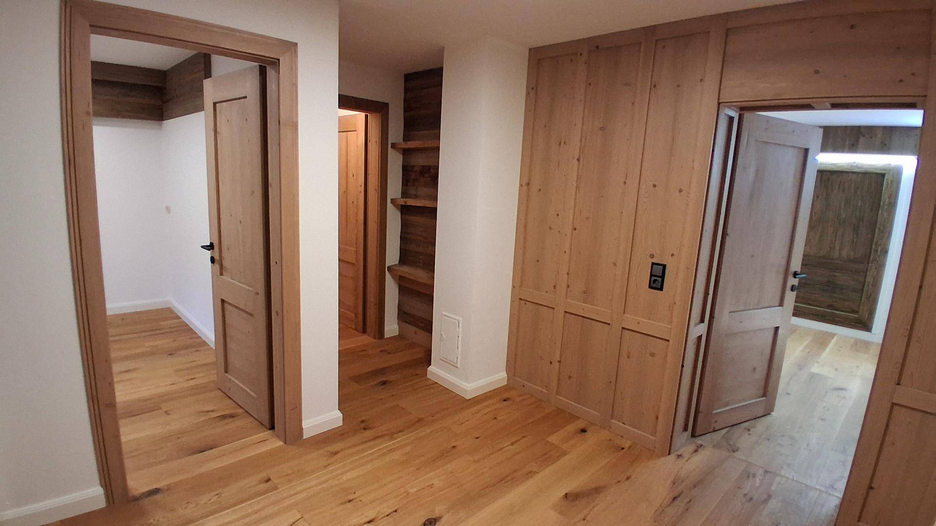 Geräumiger Flur mit durchgehendem Holzfußboden und passenden Holztüren sowie Wandverkleidungen.