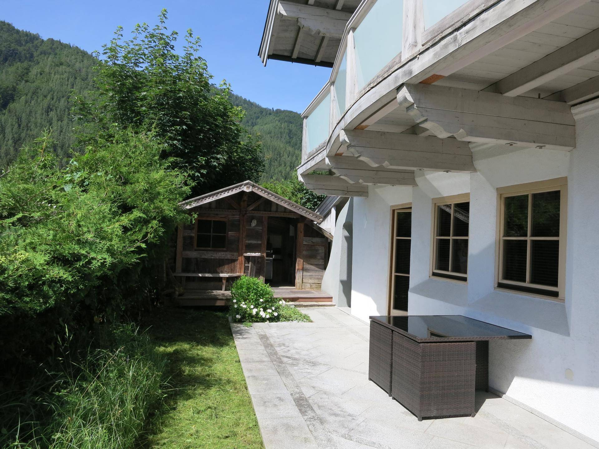 Gemütliche Terrasse mit Gartenmöbeln, Rasenfläche und einem charmanten Holzschuppen im Hintergrund.