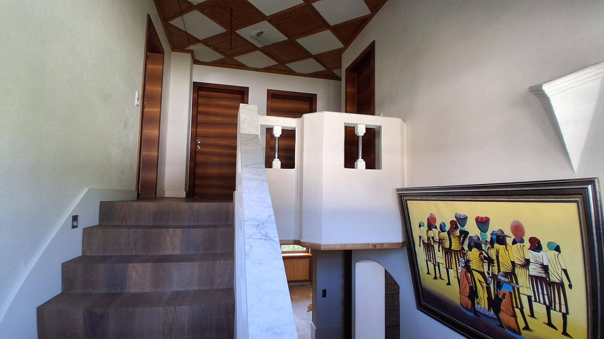 Treppenaufgang mit Holzstufen, weißem Geländer und Kunstwerk an der Wand.