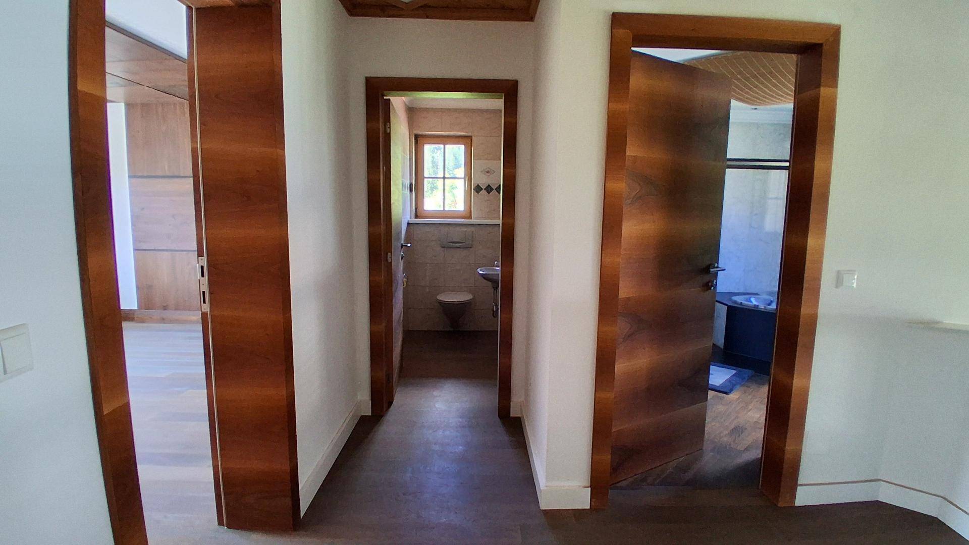 Flur mit Holztüren und dunklem Holzboden, der zu verschiedenen Zimmern führt.