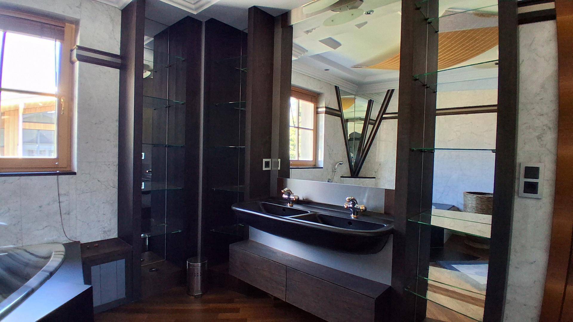 Modernes Badezimmer mit Doppelwaschbecken, Marmorfliesen und großen Spiegeln.