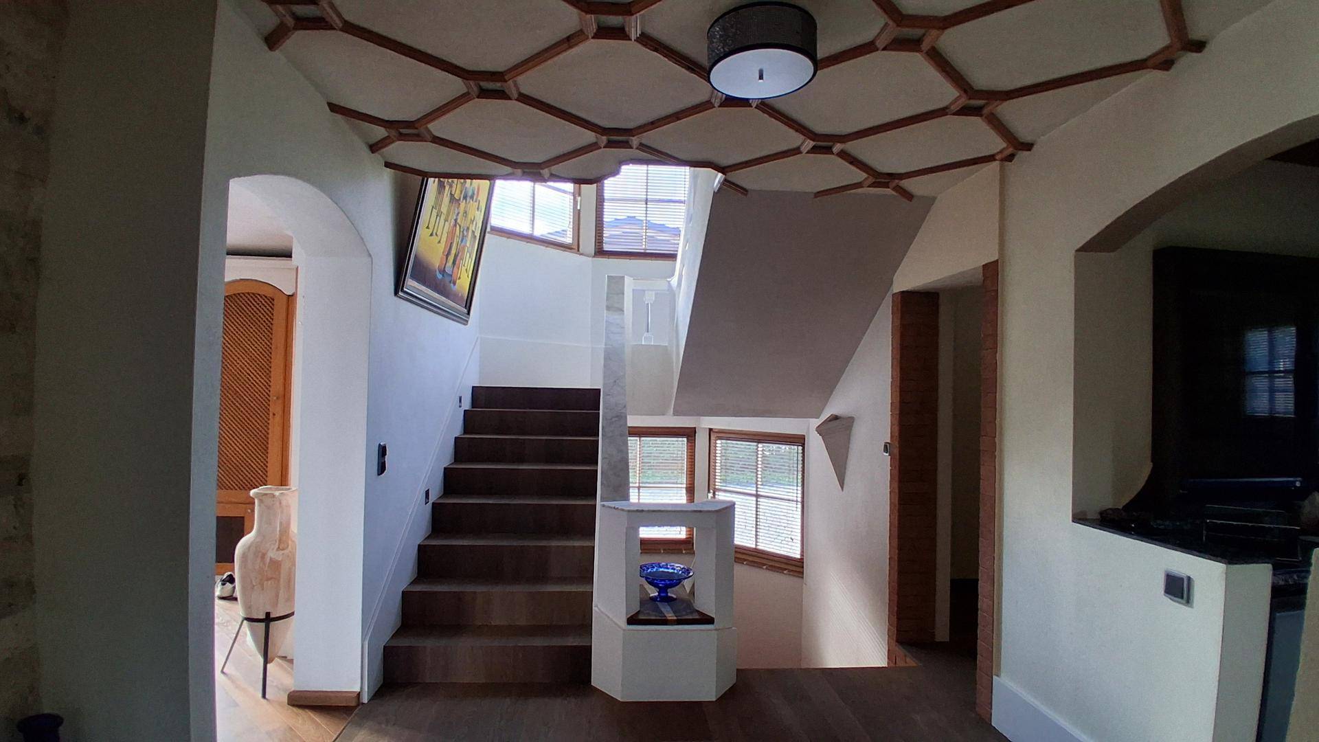 Heller Eingangsbereich mit Holztreppe, dekorativer Decke und natürlichem Lichteinfall.