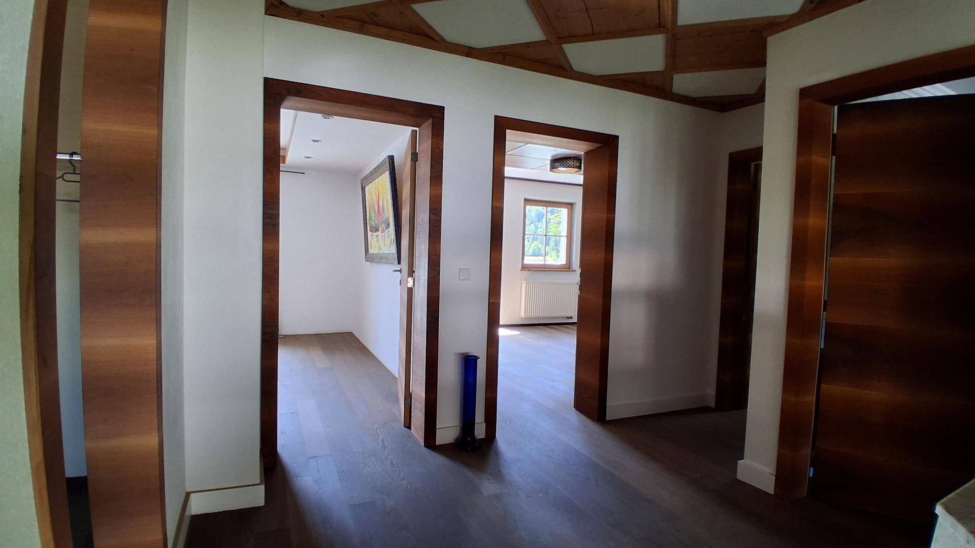 Geräumiger Flur mit Holztüren und dunklem Parkettboden, der zu weiteren Räumen führt.