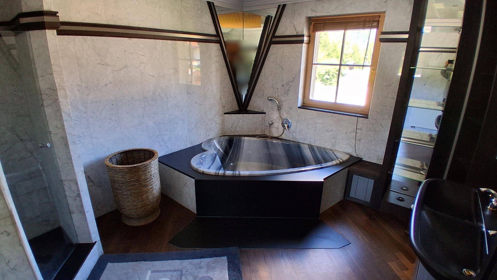 Luxuriöses Badezimmer mit Herz-förmiger Badewanne, Marmorfliesen und Holzboden.