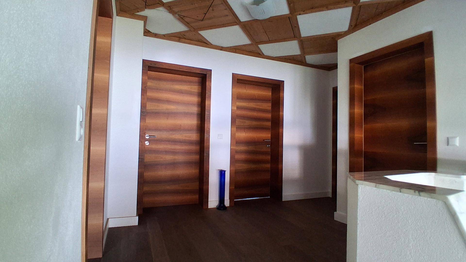 Flur mit Holztüren, dunklem Parkettboden und dekorativer Holzdecke.