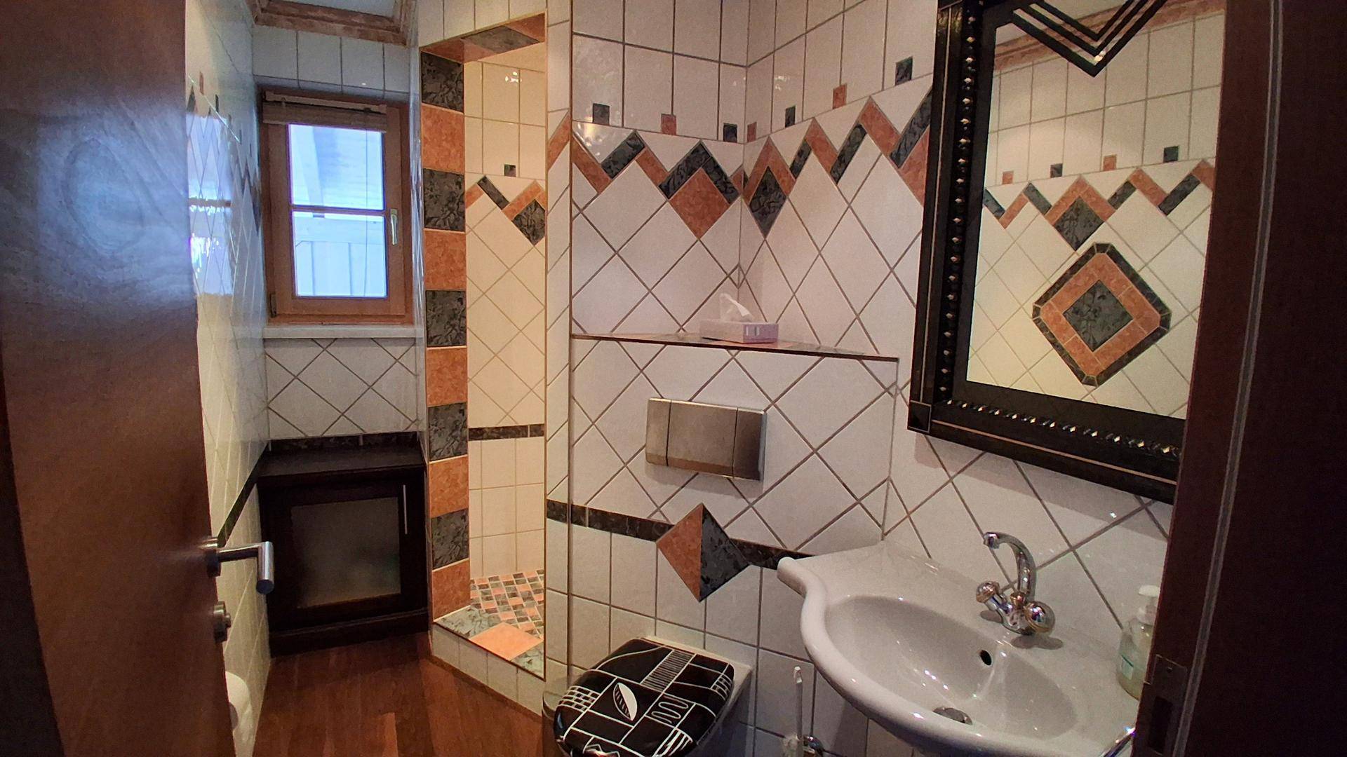 Kleines Badezimmer mit Duschkabine, WC und farbenfrohen Fliesen im Retro-Stil.