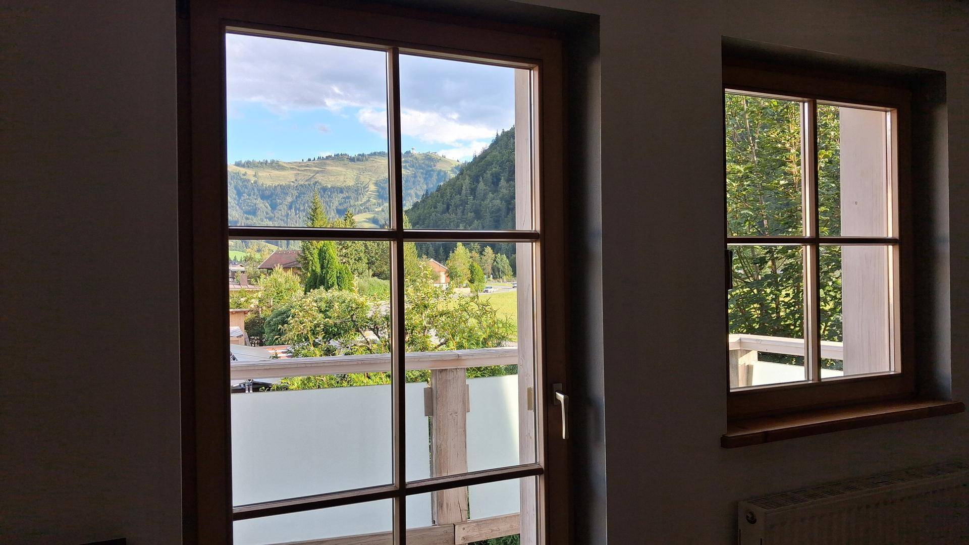 Fenster mit Blick auf die grüne Berglandschaft und den blauen Himmel.