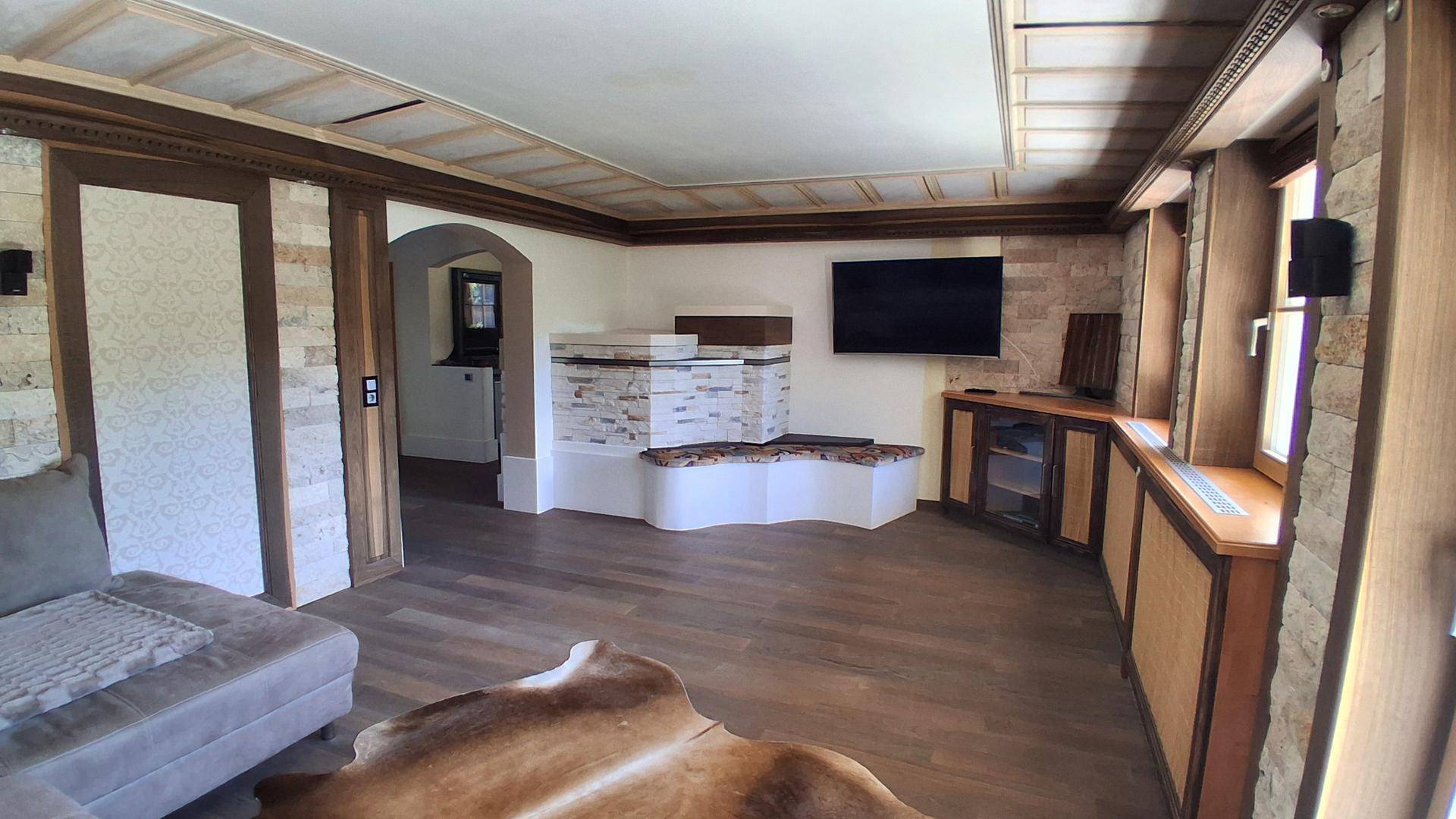 Wohnzimmer mit Kamin, Holzboden und integriertem TV-Bereich.