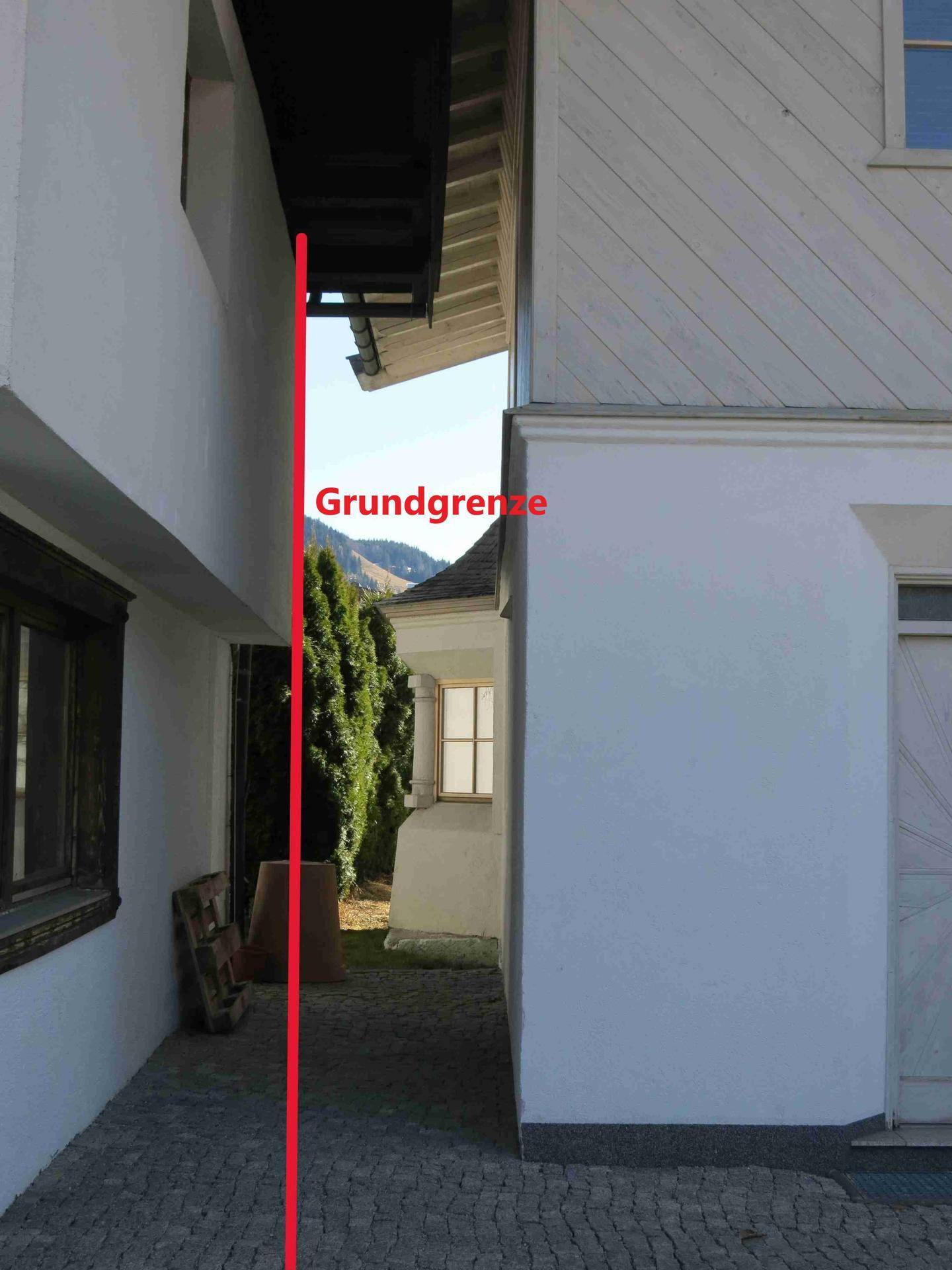 Seitenansicht des Hauses mit gepflastertem Weg und der eingezeichneten Grundstücksgrenze.