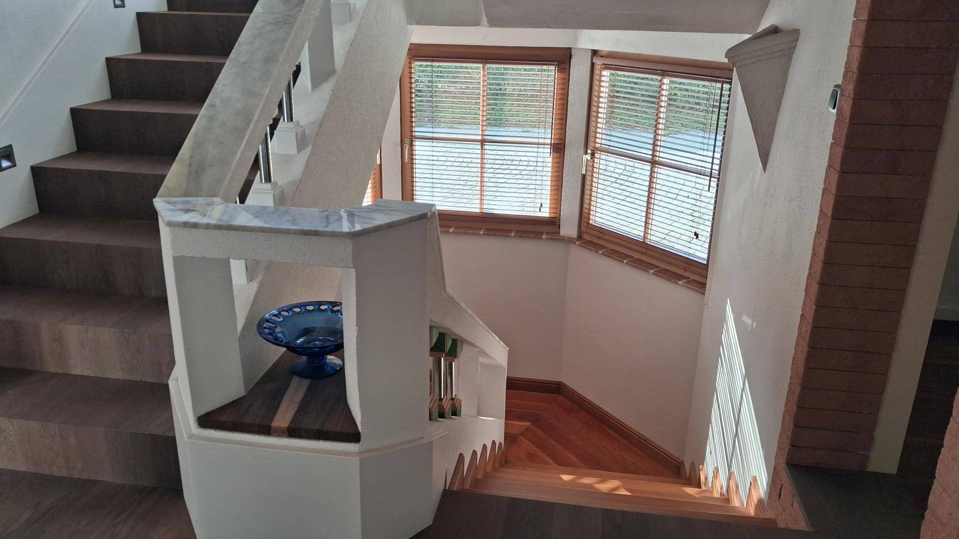 Elegante Holztreppe mit weißem Geländer und einem Erkerfenster, das natürliches Licht hereinlässt.