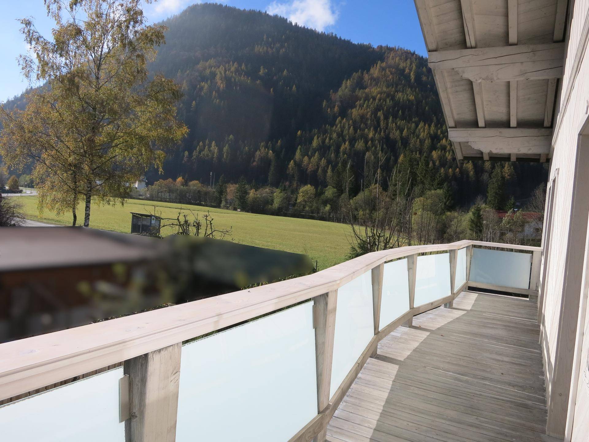 Geräumiger Balkon mit Glasgeländer und weitem Blick auf die umliegende Natur.