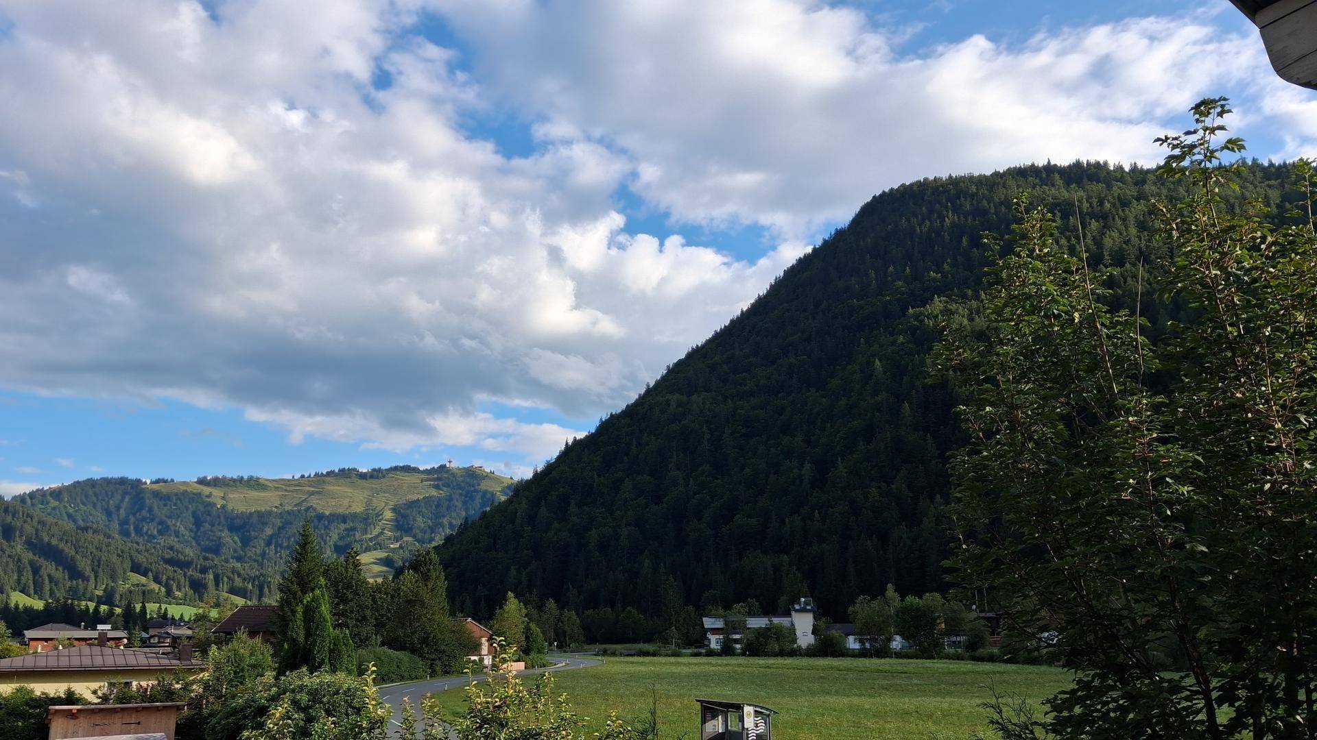 Panoramablick auf die grüne Berglandschaft unter einem bewölkten Himmel.