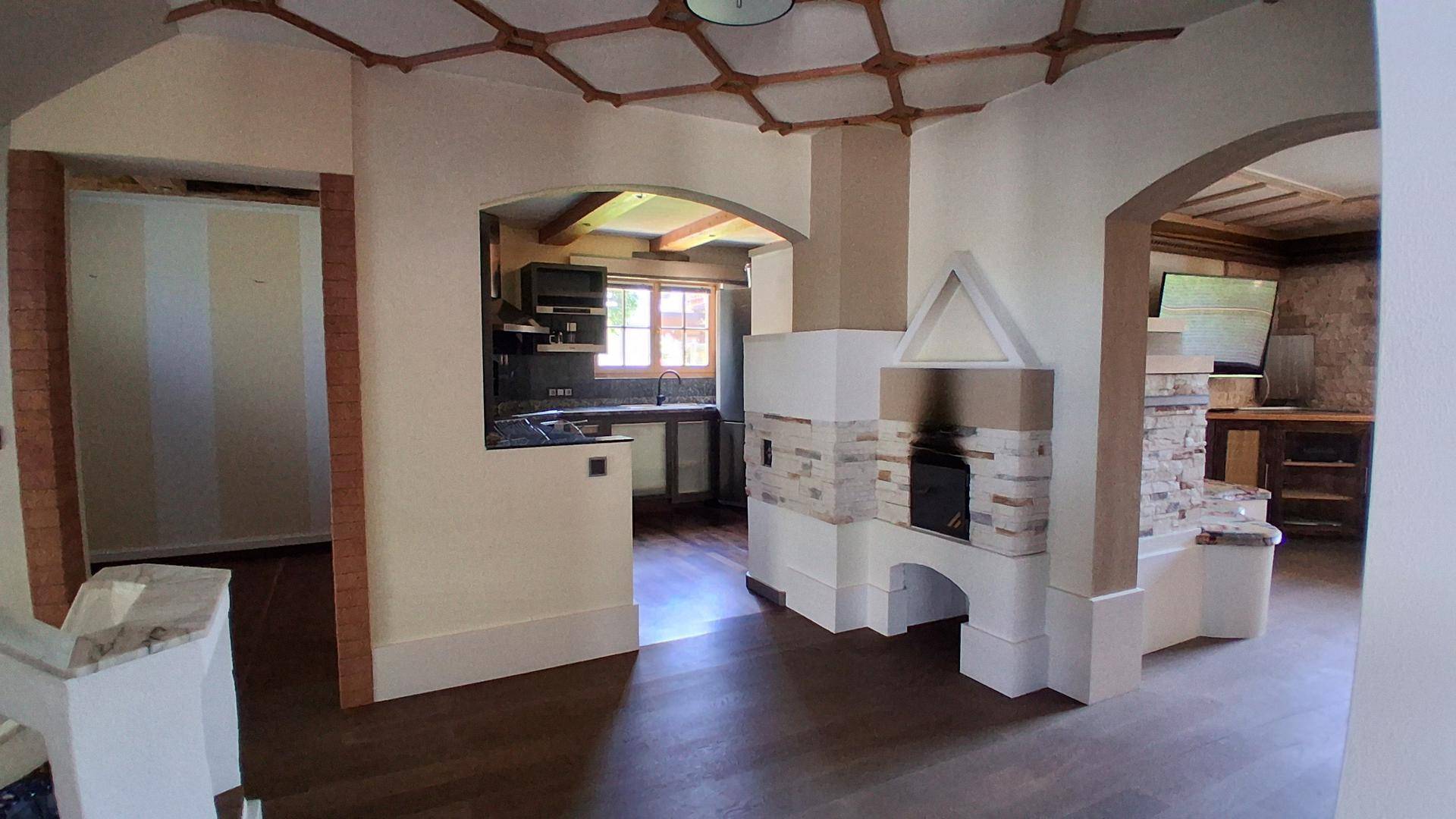 Offener Wohnbereich mit Kamin und Blick in die angrenzende Küche.