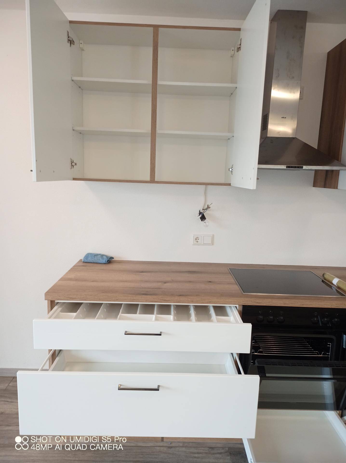 Detailansicht einer neuen Küche mit Besteckschublade, Dunstabzugshaube und Holz-Arbeitsplatte.