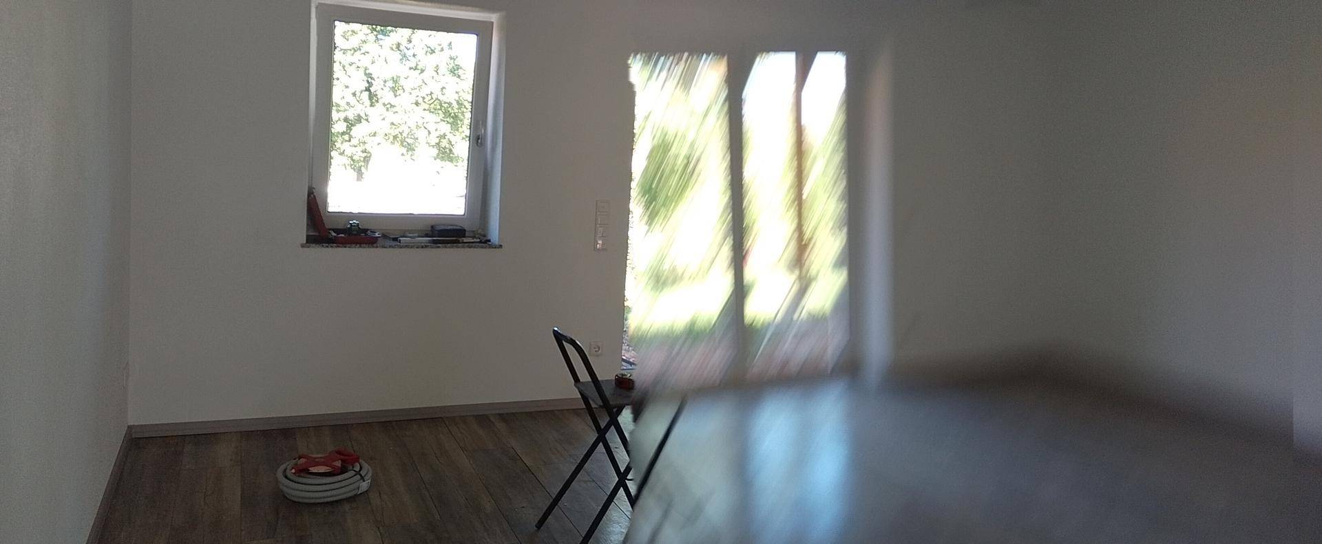 Helles Wohnzimmer mit Holzboden und Zugang zu einem Außenbereich, umgeben von Natur.