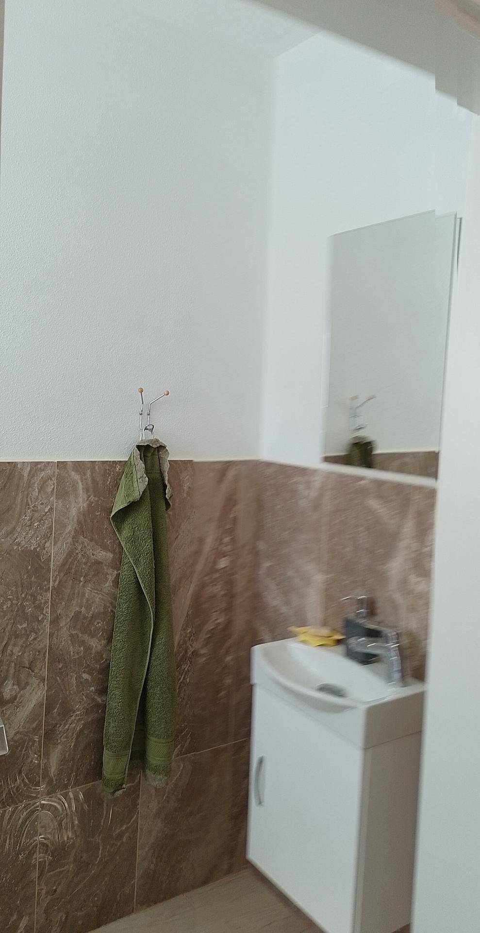 Helles Gäste-WC mit Waschbecken, Spiegel und braunen Wandfliesen, funktional und sauber.