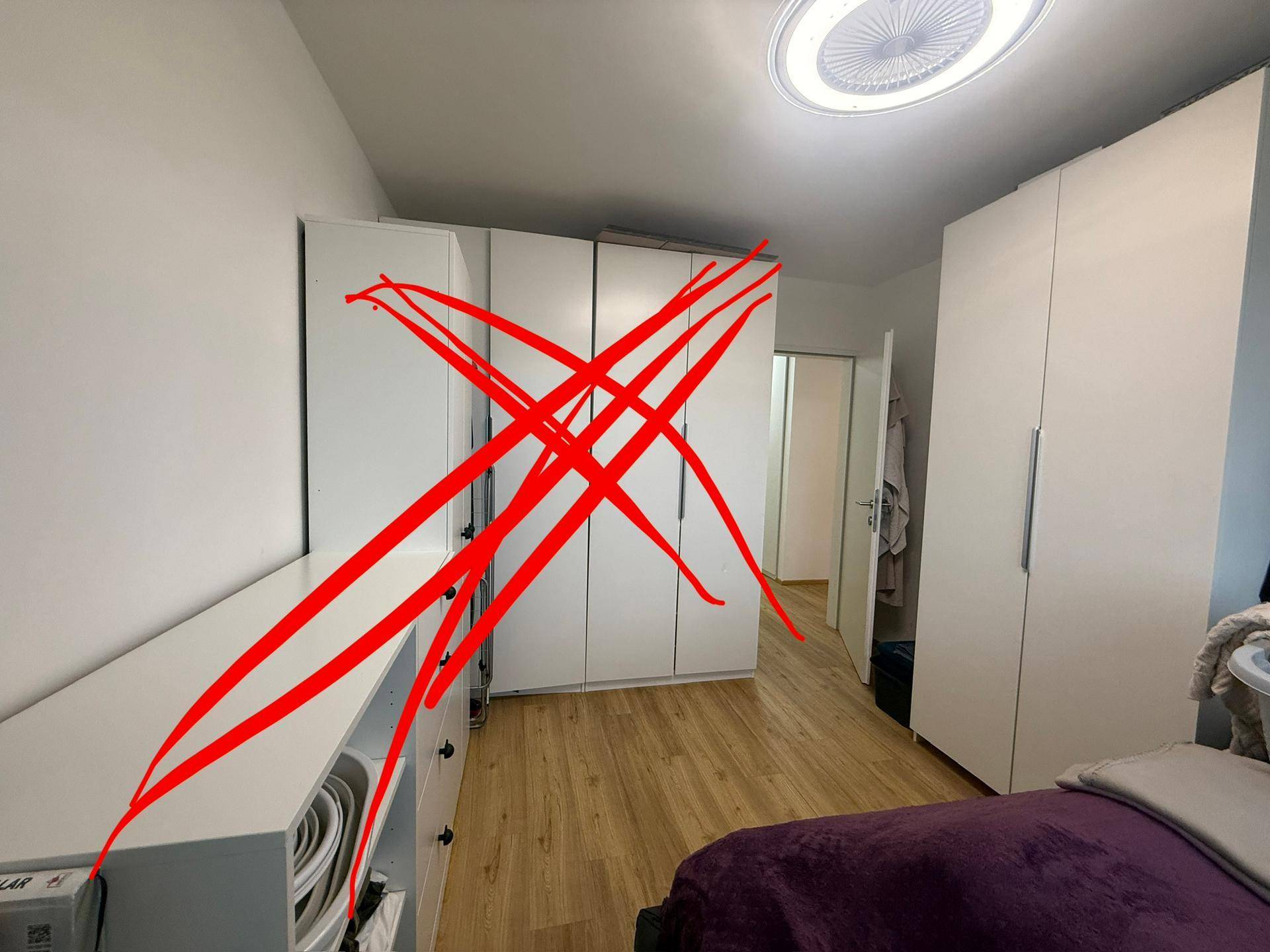 Schlafzimmer mit praktischen weißen Einbauschränken und hellem Holzboden für viel Stauraum.