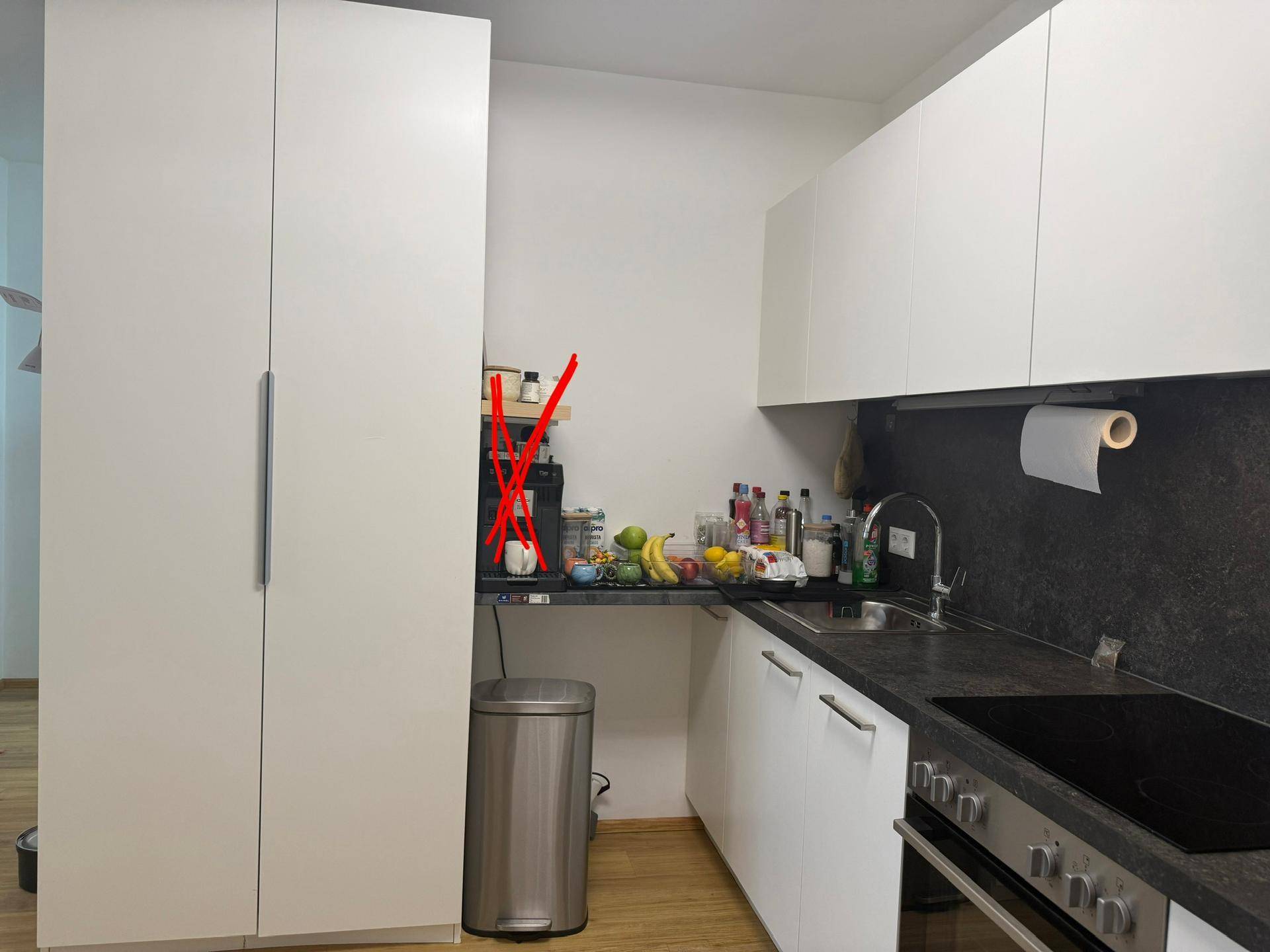 Moderne Küche mit weißen Schränken, dunkler Arbeitsplatte und integrierten Geräten.