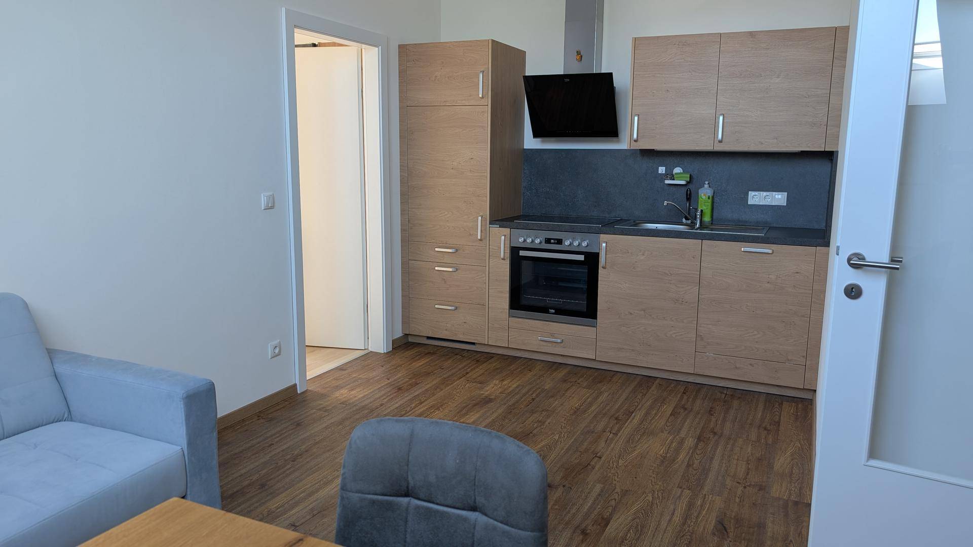 Moderne Küchenzeile mit Holzfronten und integrierten Geräten in einem offenen Wohnbereich.