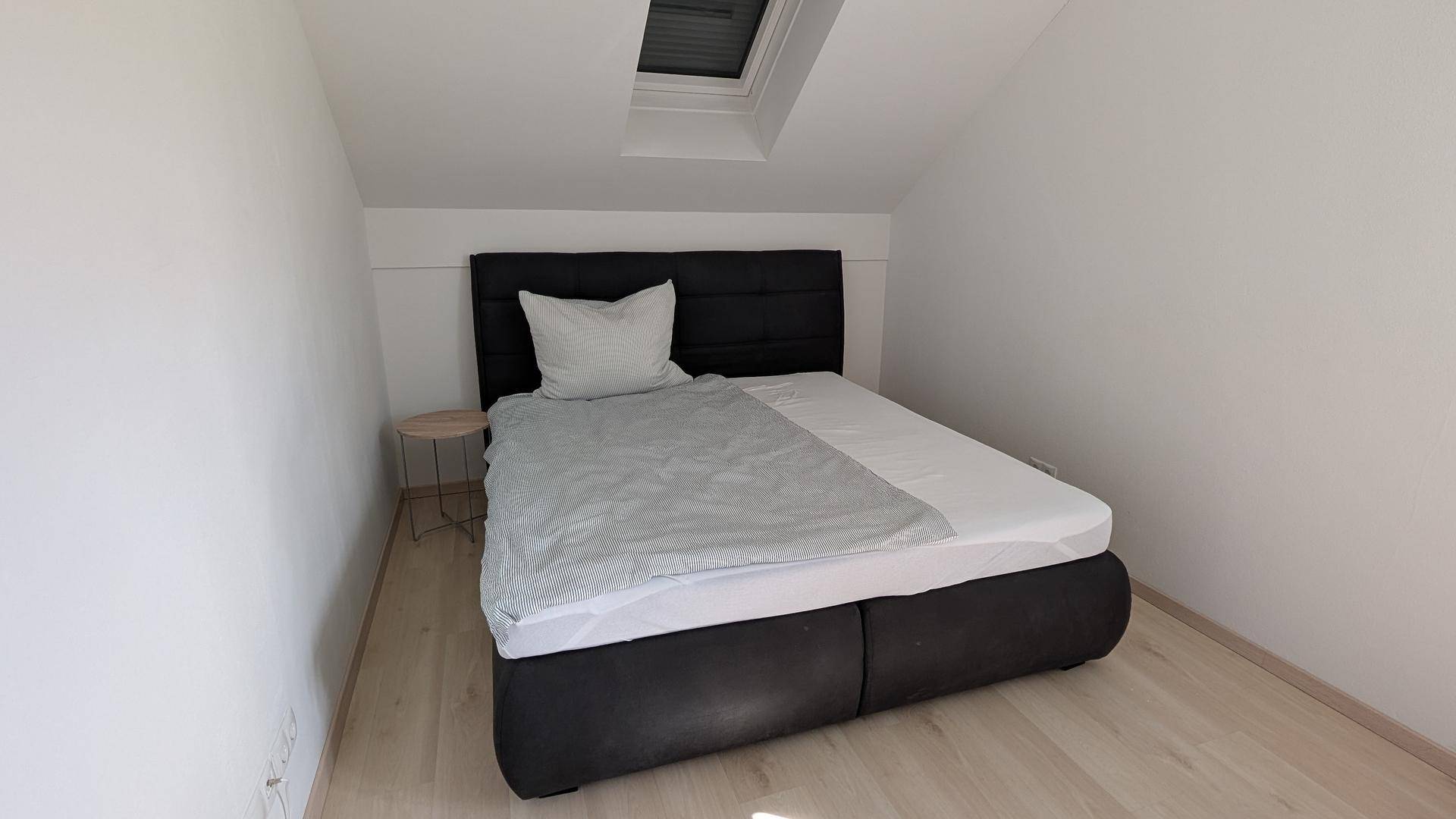 Gemütliches Schlafzimmer im Dachgeschoss mit Doppelbett und Dachfenster für natürliche Belichtung.