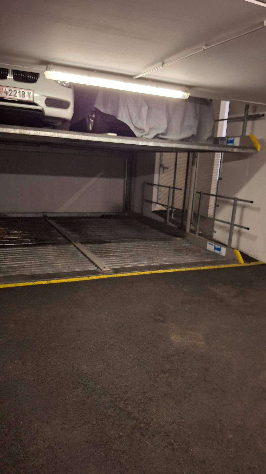 Tiefgaragenstellplatz mit mechanischem Doppelparkersystem und einem Fahrzeug auf der oberen Ebene.