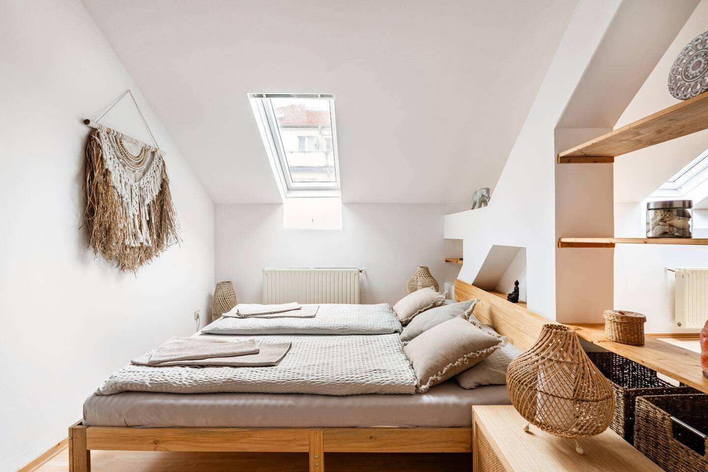 Helles Schlafzimmer im Dachgeschoss mit Doppelbett, integrierten Regalen und Dachfenster.