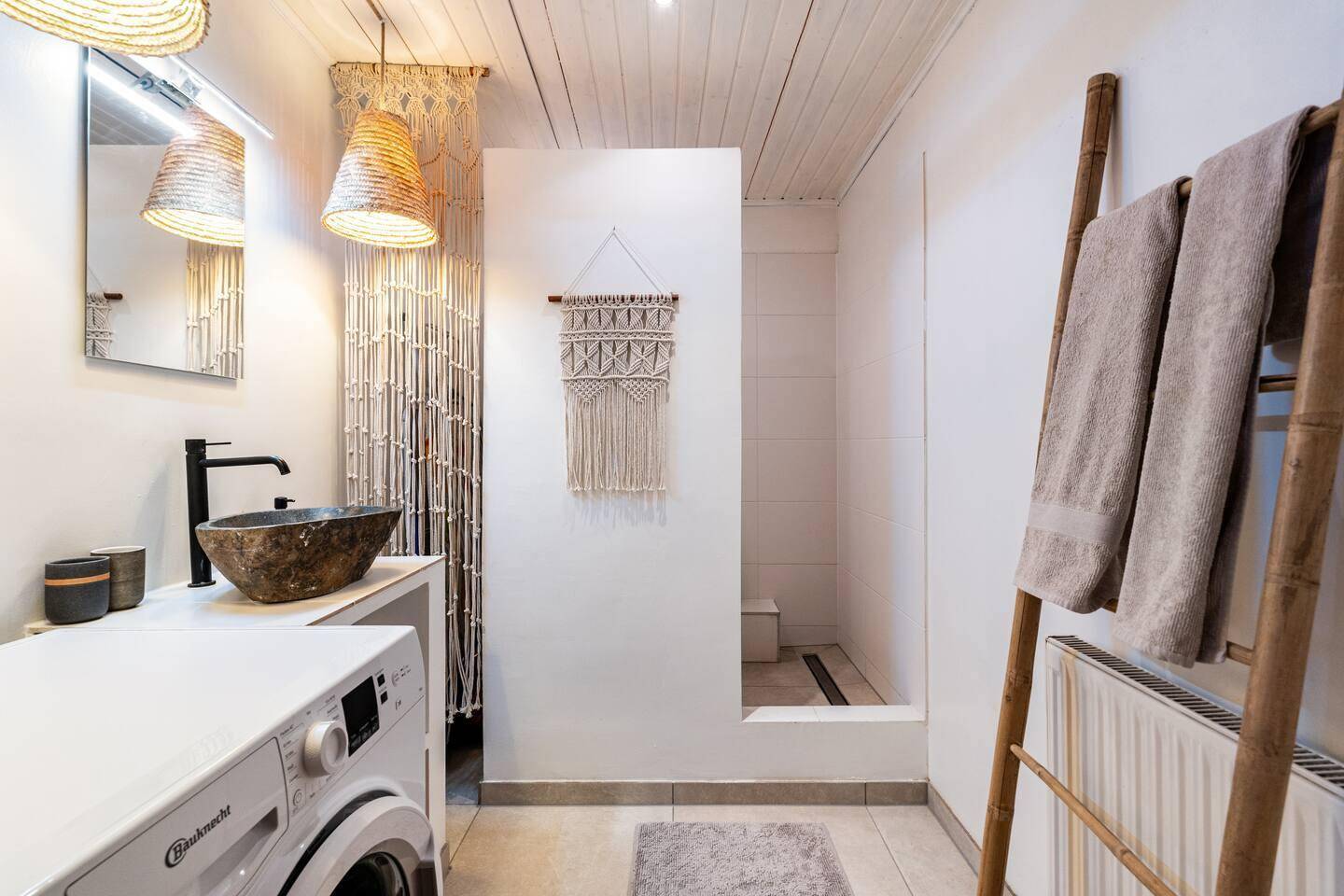 Modernes Badezimmer mit begehbarer Dusche, Steinswaschbecken und Waschmaschine.