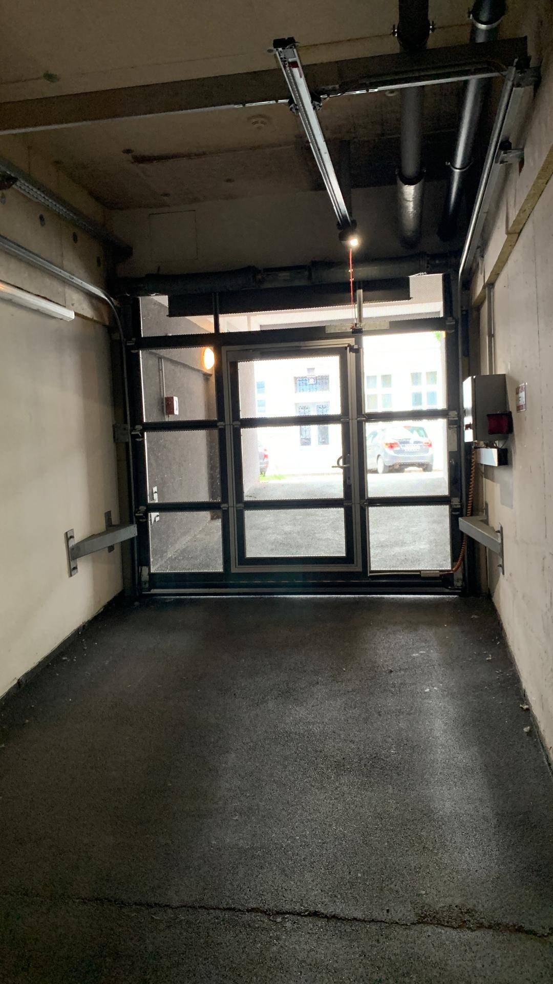 Innenansicht einer Tiefgarage mit Blick auf das automatische Garagentor und die Ausfahrt.