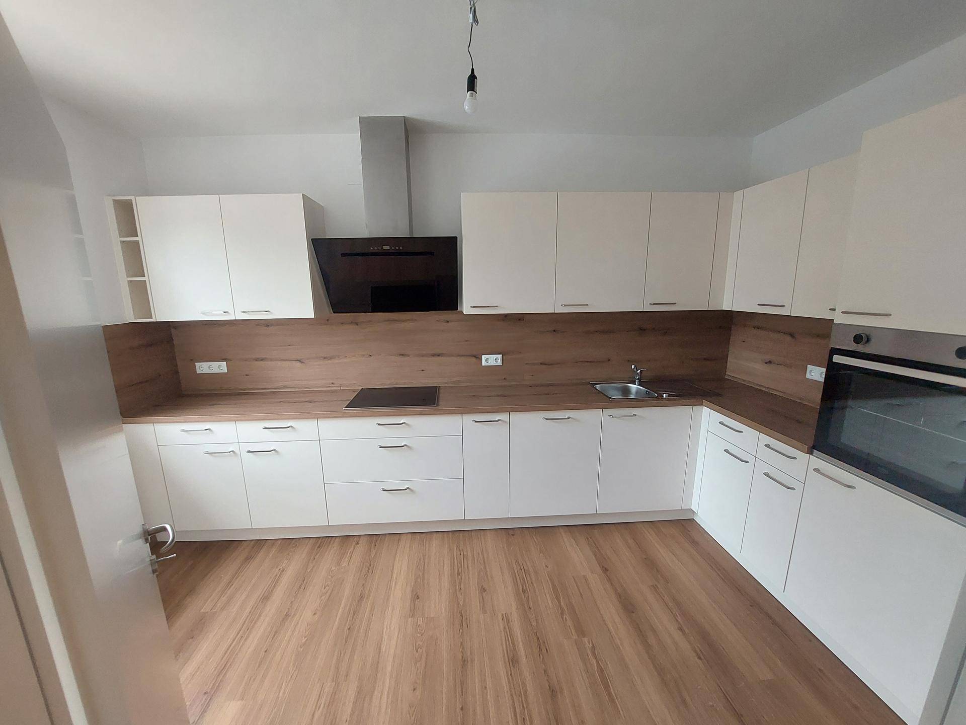 Moderne Einbauküche mit weißen Schränken, Holzarbeitsplatte und integrierten Geräten.