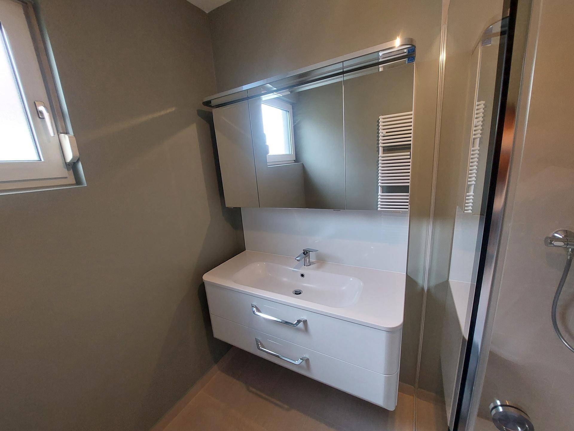 Waschtisch mit Unterschrank und Spiegelschrank in einem modernen Badezimmer.