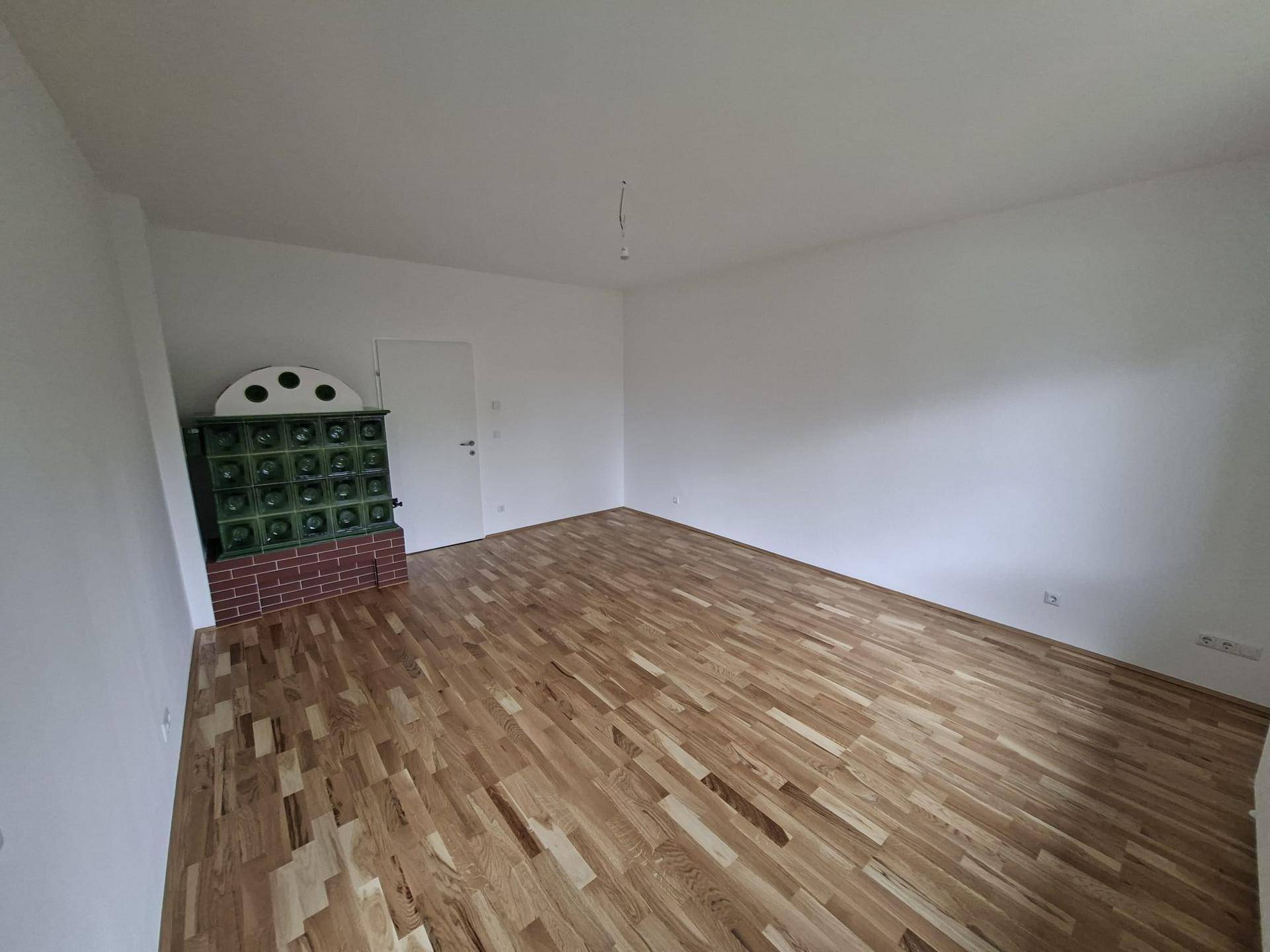 Wohnzimmer mit traditionellem Kachelofen und hellem Parkettboden.