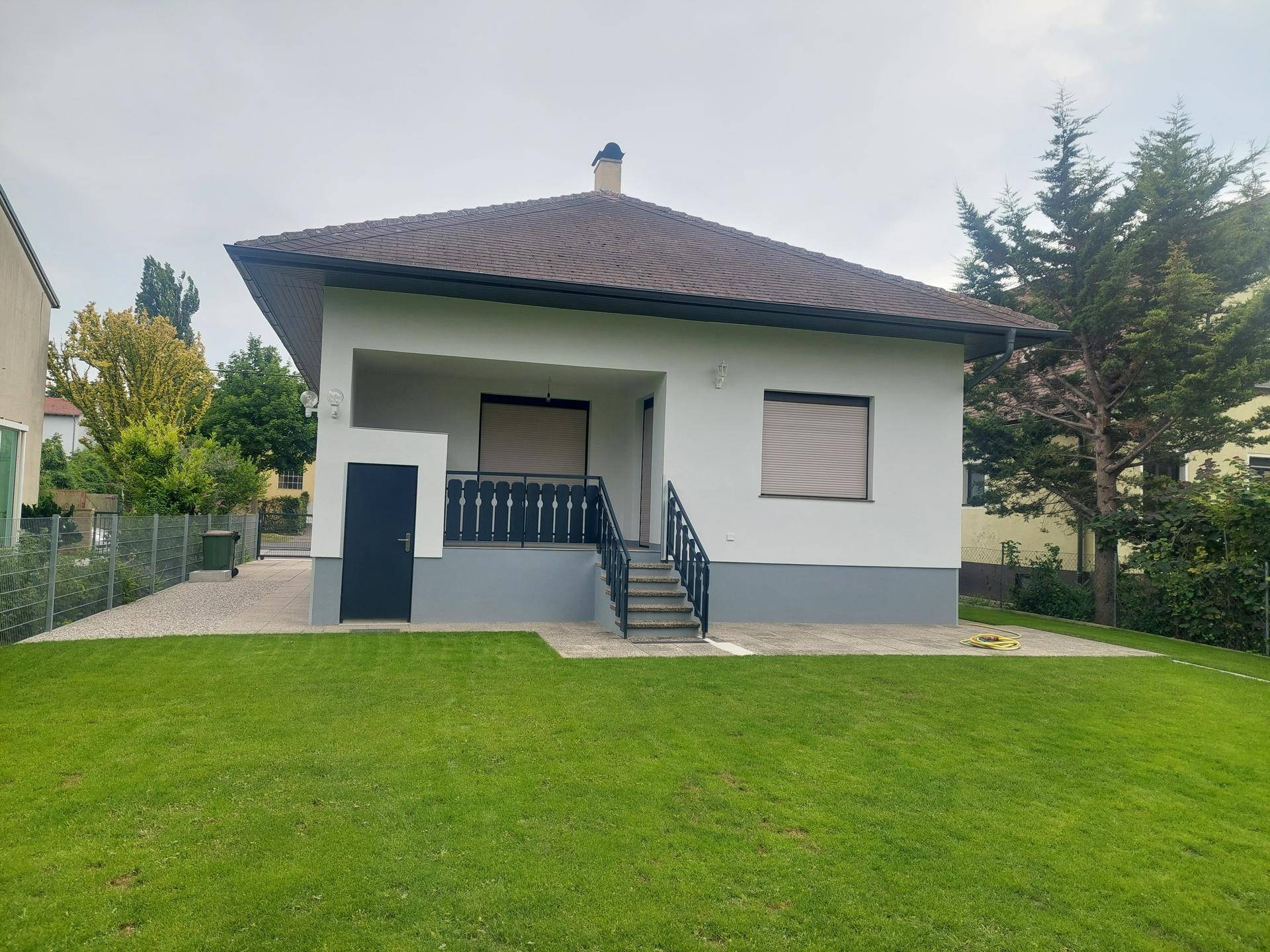 Rückansicht des Hauses mit großem Rasen und überdachtem Eingangsbereich.