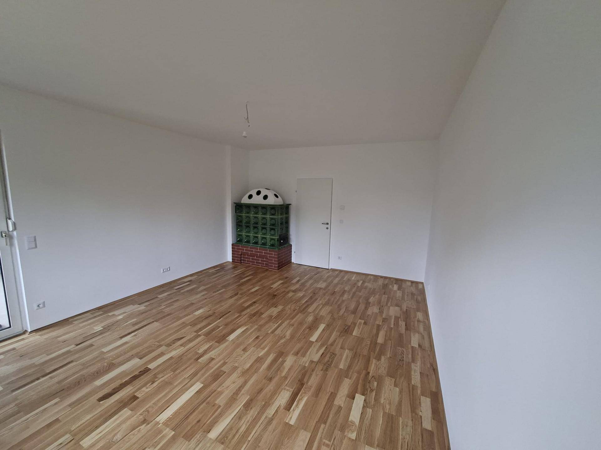 Geräumiges Wohnzimmer mit Kachelofen und Parkettboden, bereit zur individuellen Gestaltung.