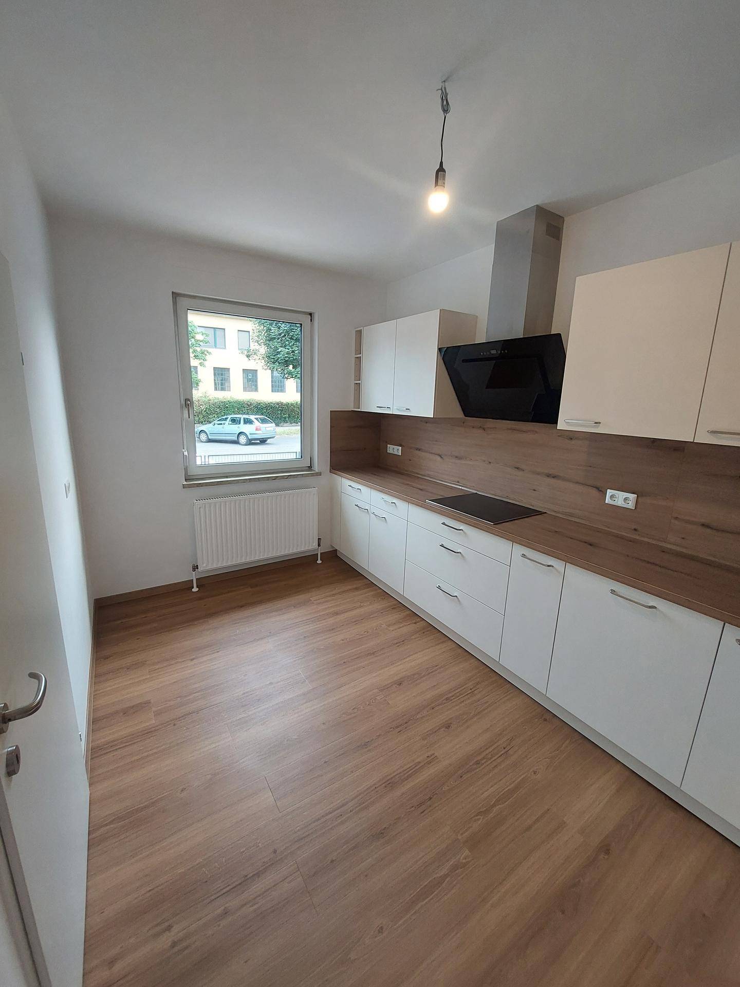 Helle Küche mit Fenster, modernen Einbauschränken und Laminatboden.