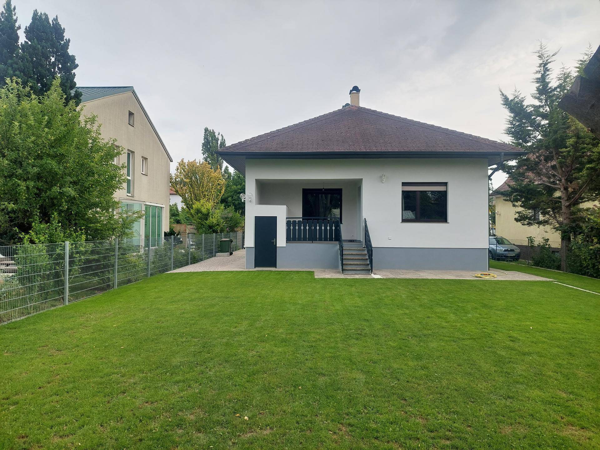 Rückansicht des Hauses mit großem Rasen und Zugang zu einer überdachten Terrasse.