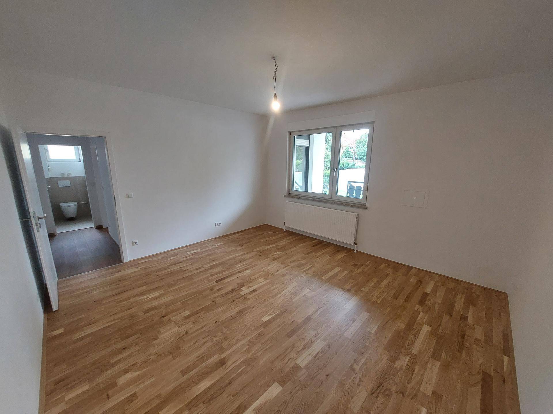Schlafzimmer mit Holzboden und Zugang zu einem angrenzenden Badezimmer.
