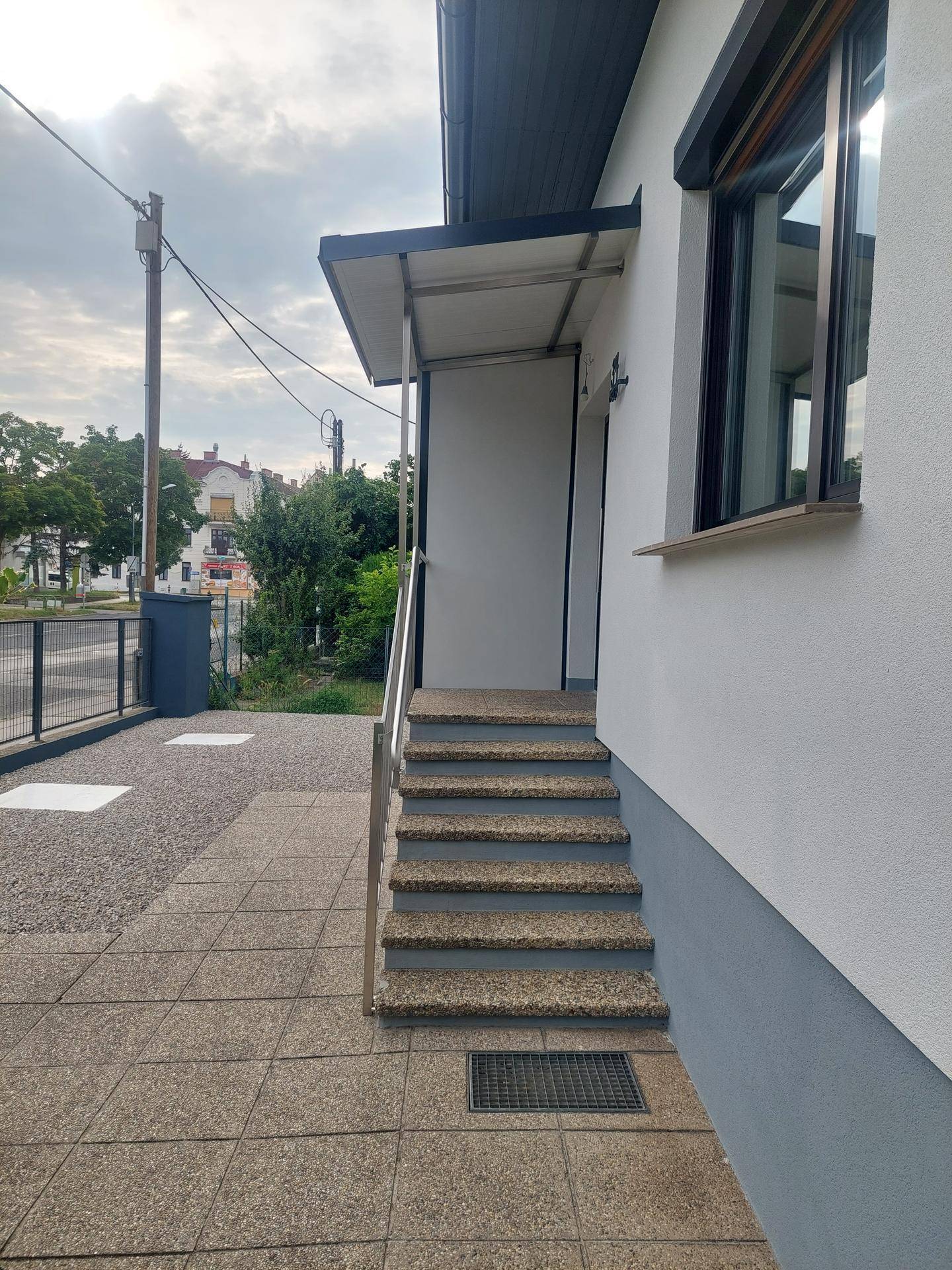 Seitlicher Blick auf den Hauseingang mit Treppe und Überdachung.